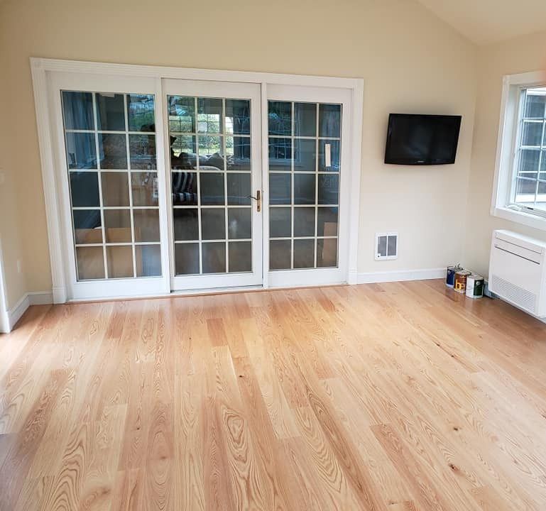 Sunroom with hardwood floor, glass door, TV, and window.