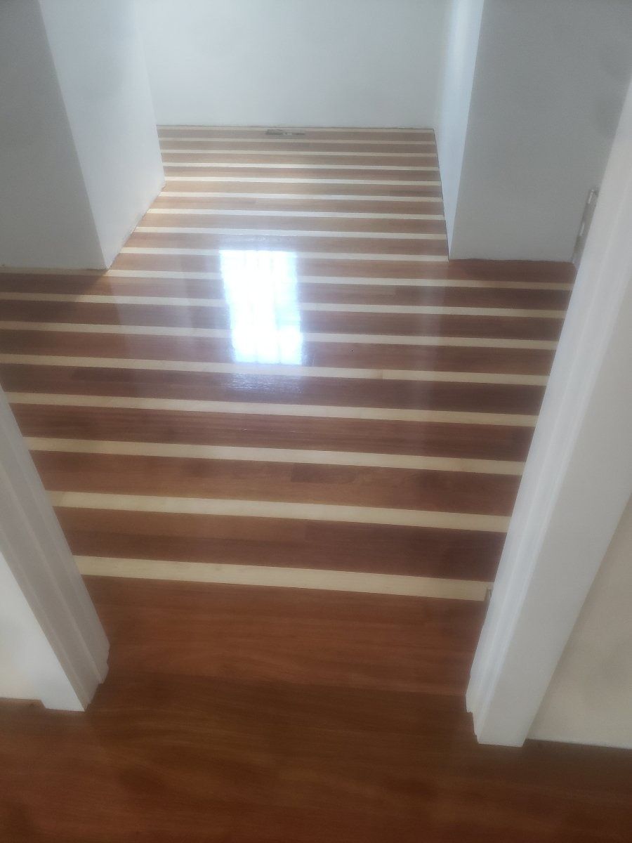 Wooden staircase with alternating dark and light treads, leading upwards toward a bright light.