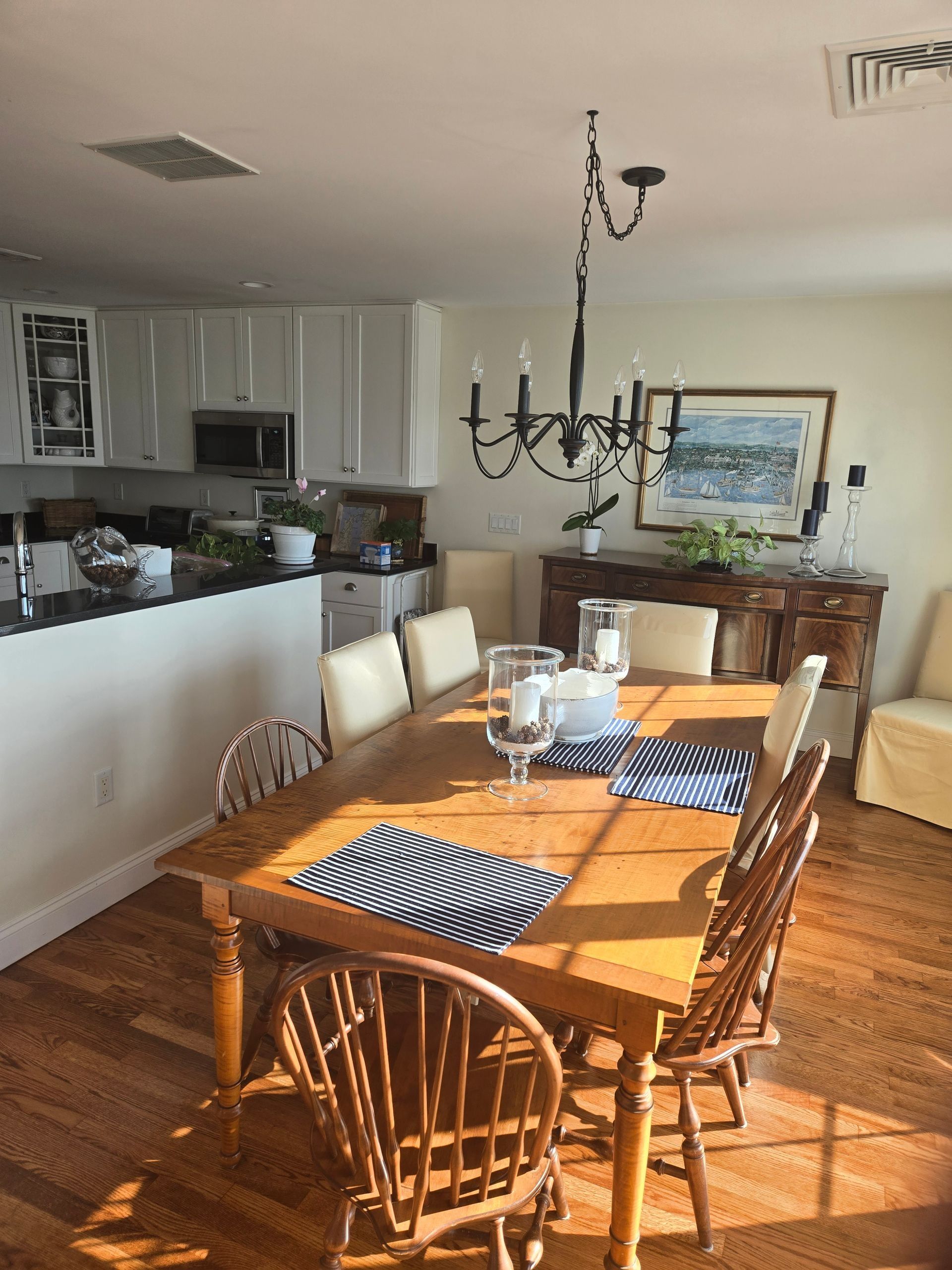 Dining room with wooden table and chairs, chandelier, and a buffet. Sunny, bright interior.