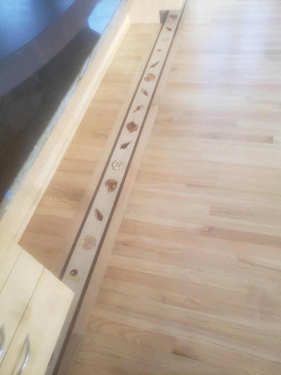 Wooden floor with decorative inlaid border of leaf and flower shapes.