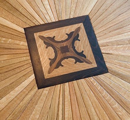 Wooden floor with ornate center square: Light wood radiates from a dark-bordered central design.