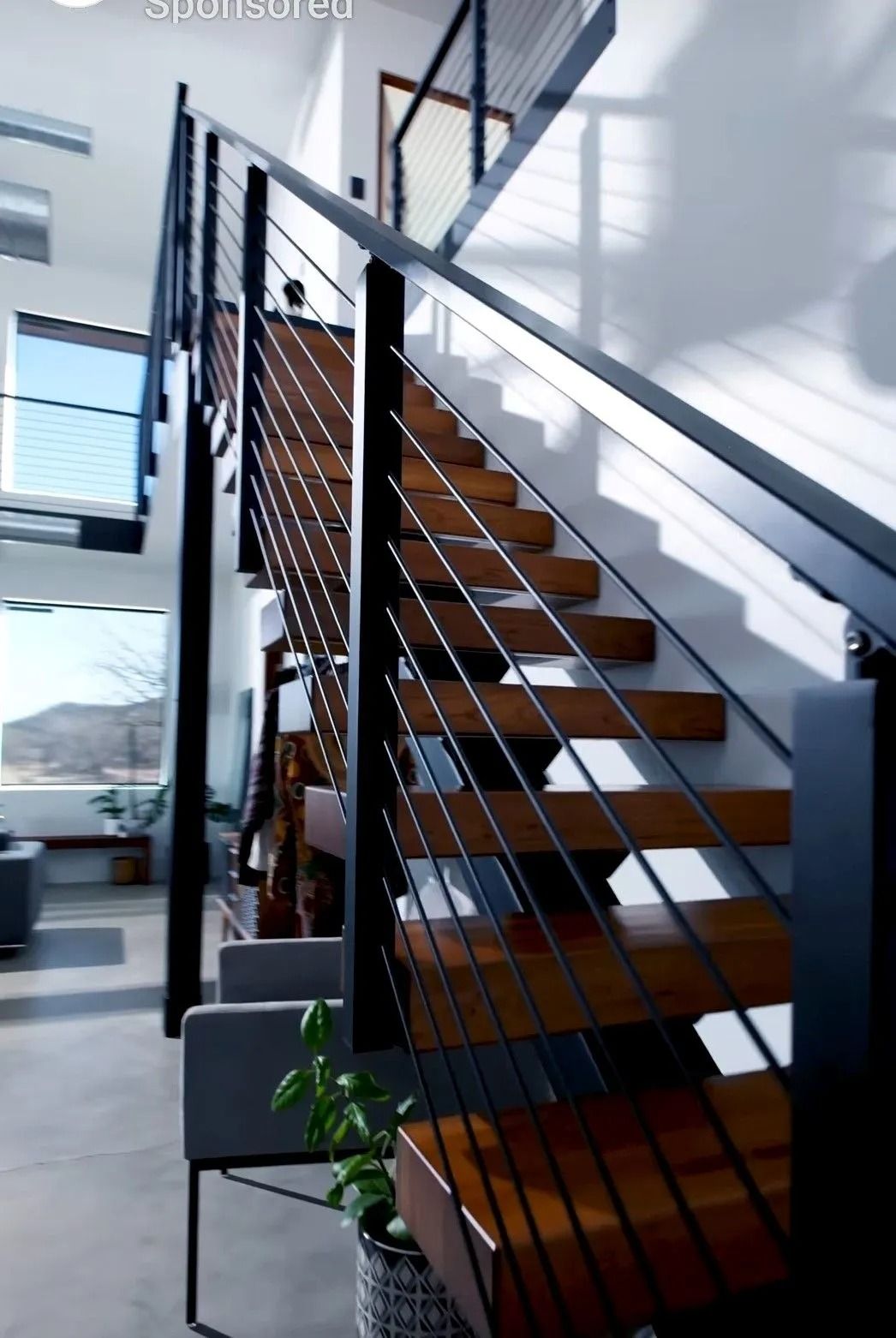 Wooden staircase with black metal railing in a modern home.