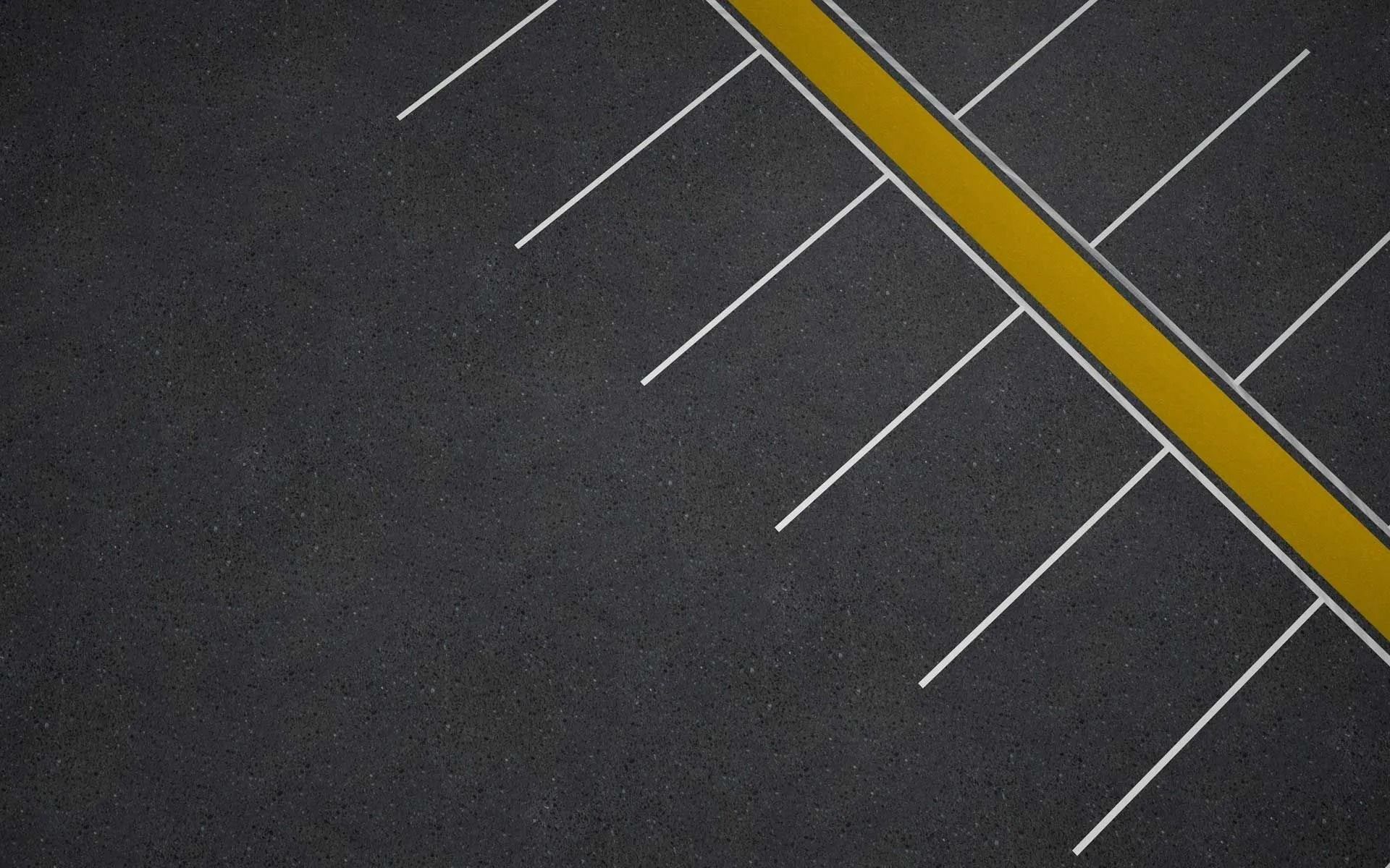 Asphalt parking lot with yellow and white painted lines for parking spaces.