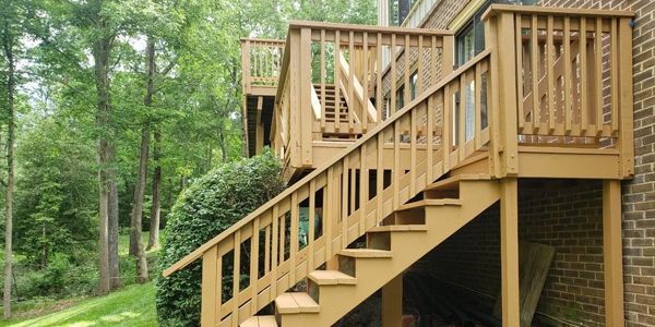 the back of a large house with a large deck and stairs leading up to it