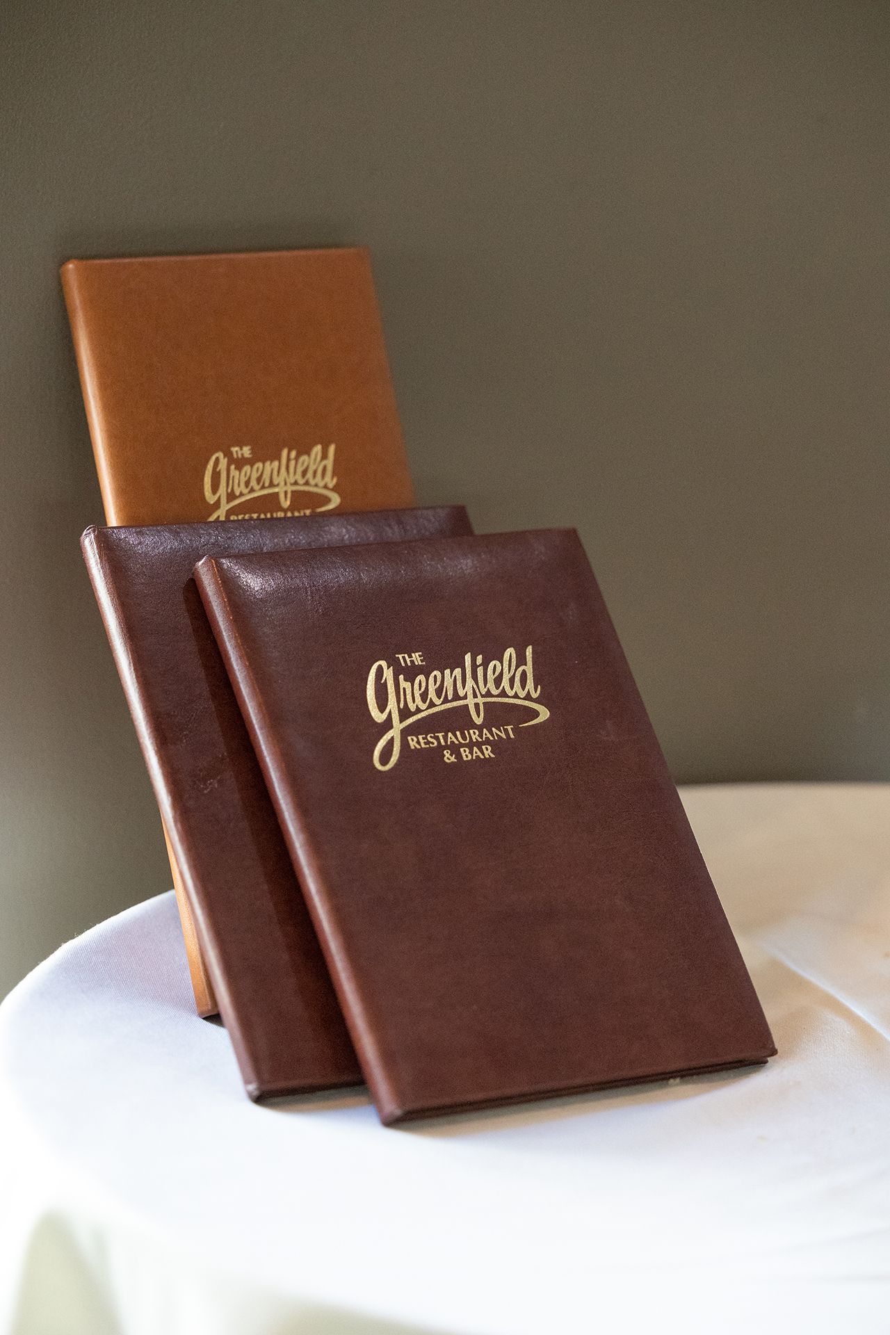 Two leather-bound books with gold lettering, one brown and one burgundy, displayed on a white surface.