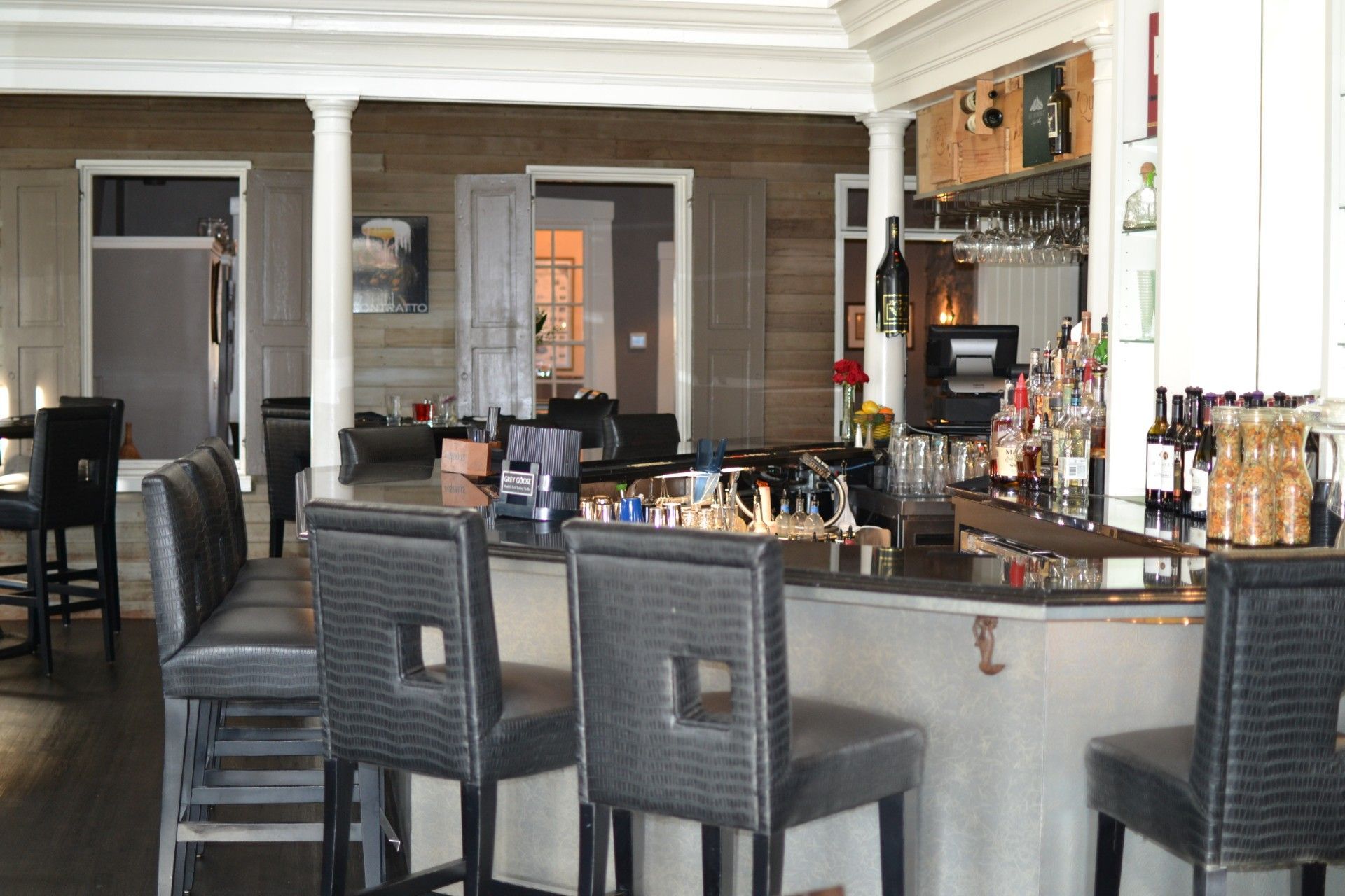 Modern home bar with granite counter, dark stools, and bottles displayed behind it