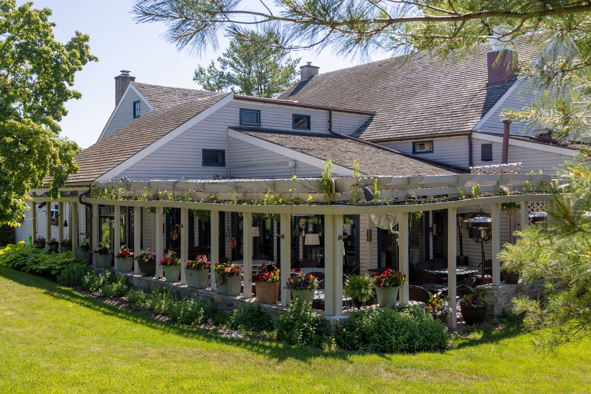 Large white house with wraparound porch and flower boxes on a sunny green lawn