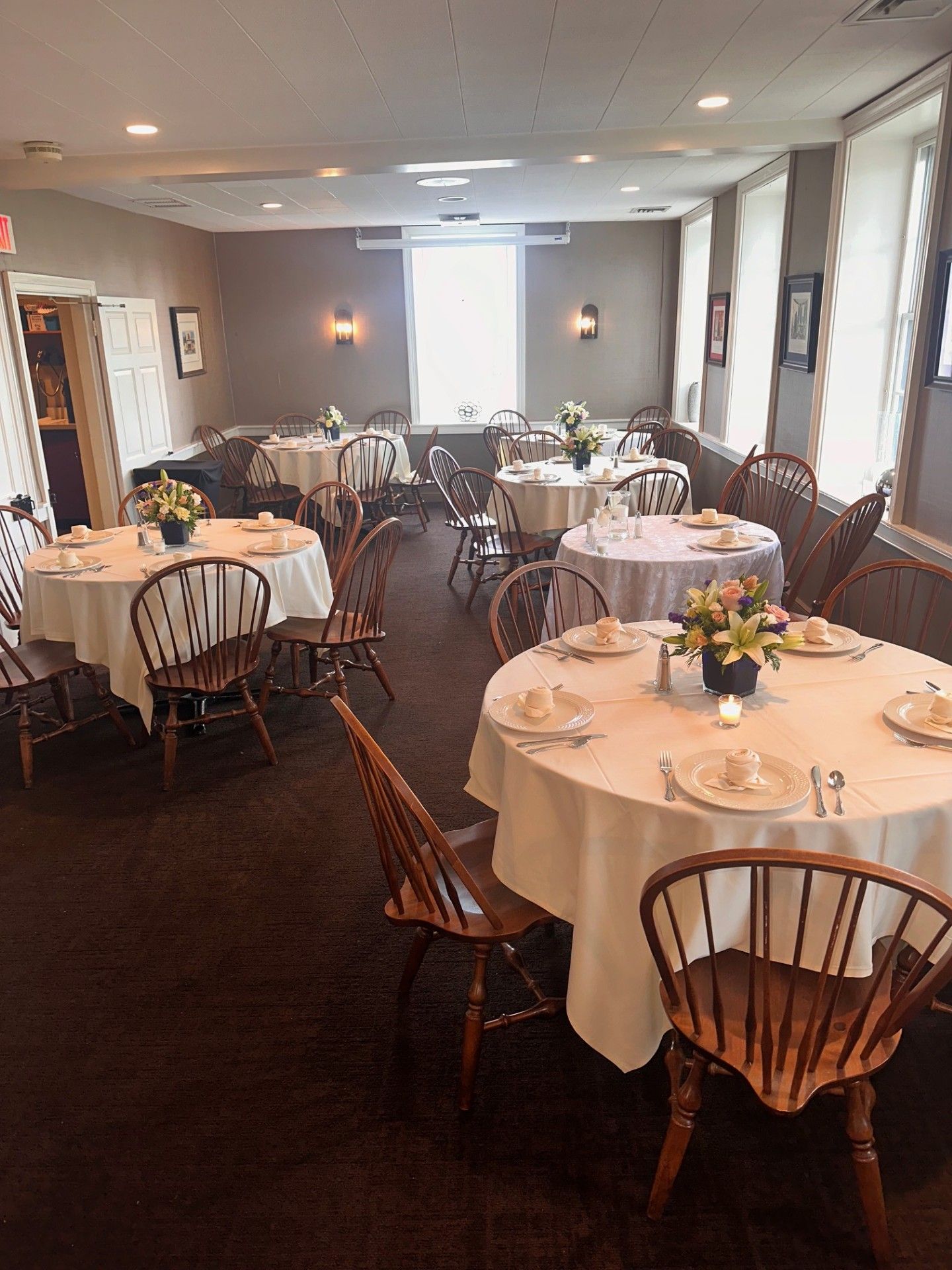 Formal dining room with round tables dressed in white tablecloths and floral centerpieces