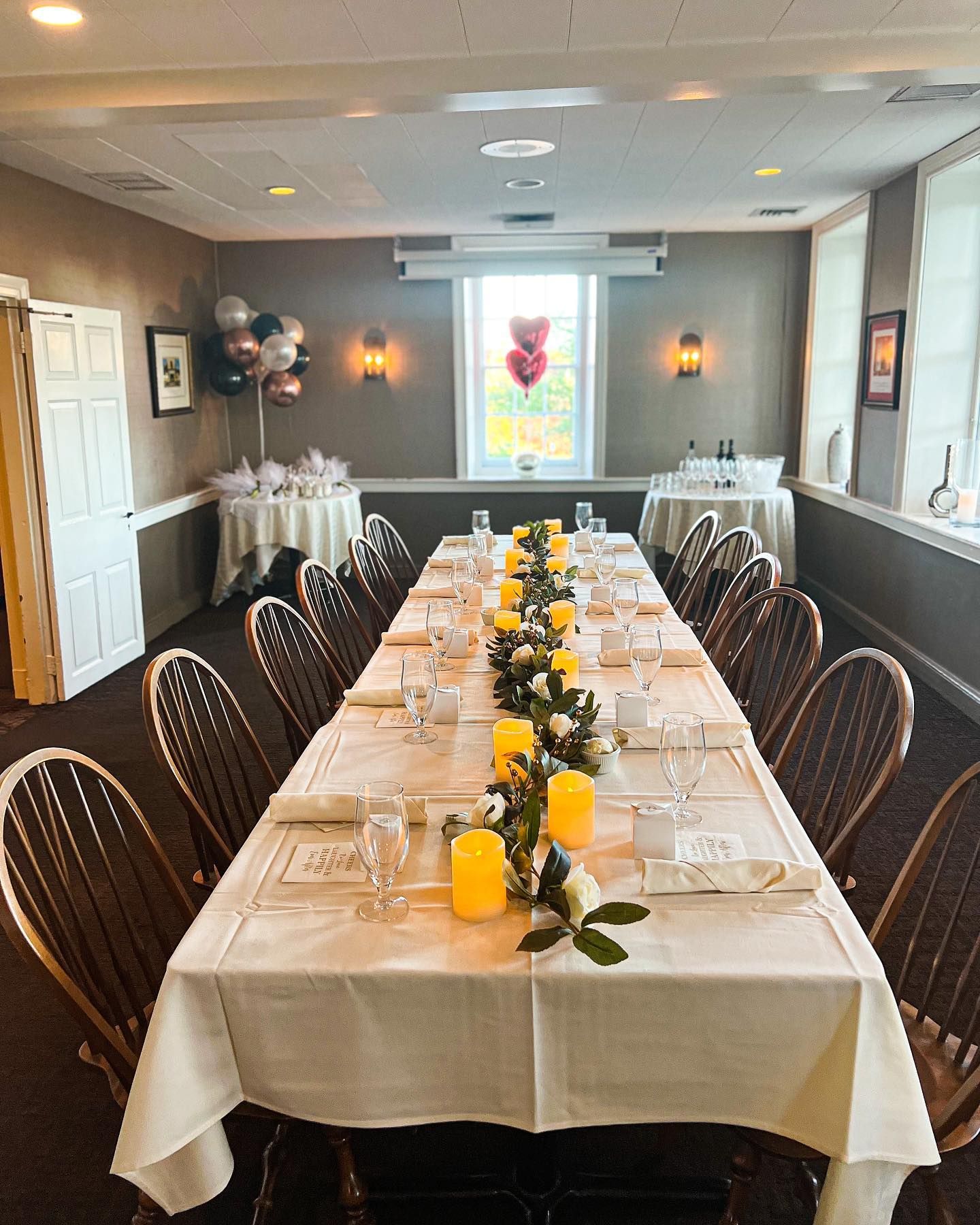 Long banquet table set with white cloth, yellow flowers, and folded napkins in a formal dining room