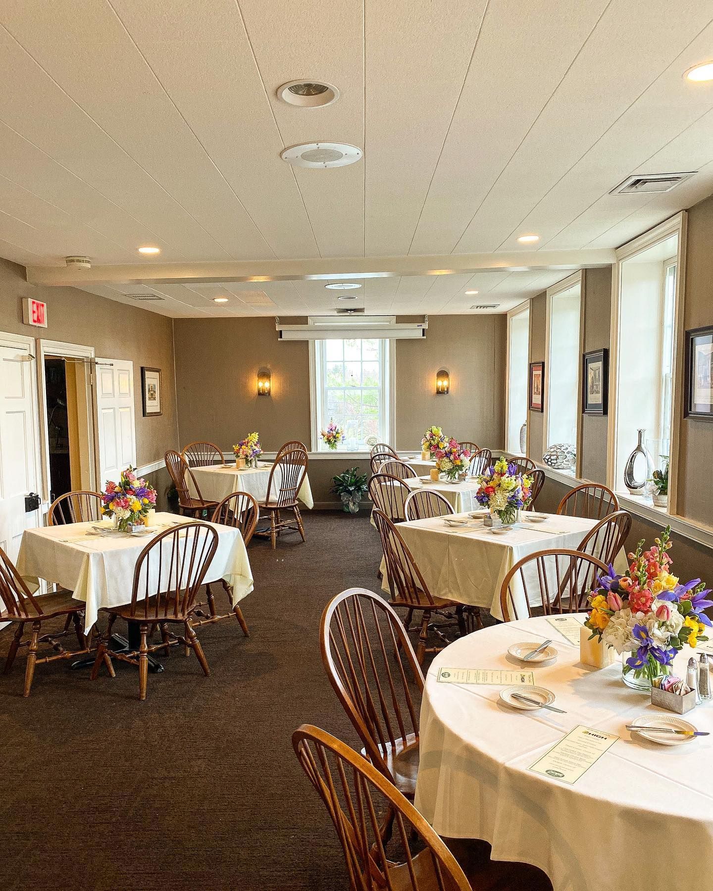 Elegant banquet room with round tables set for a formal event, decorated with floral centerpieces and place settings.