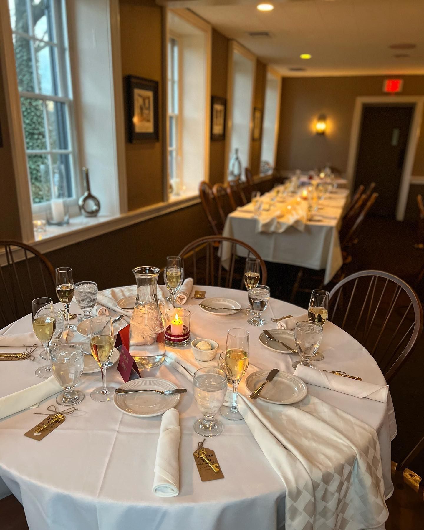 Round banquet tables set for a formal dinner in a warmly lit dining room.