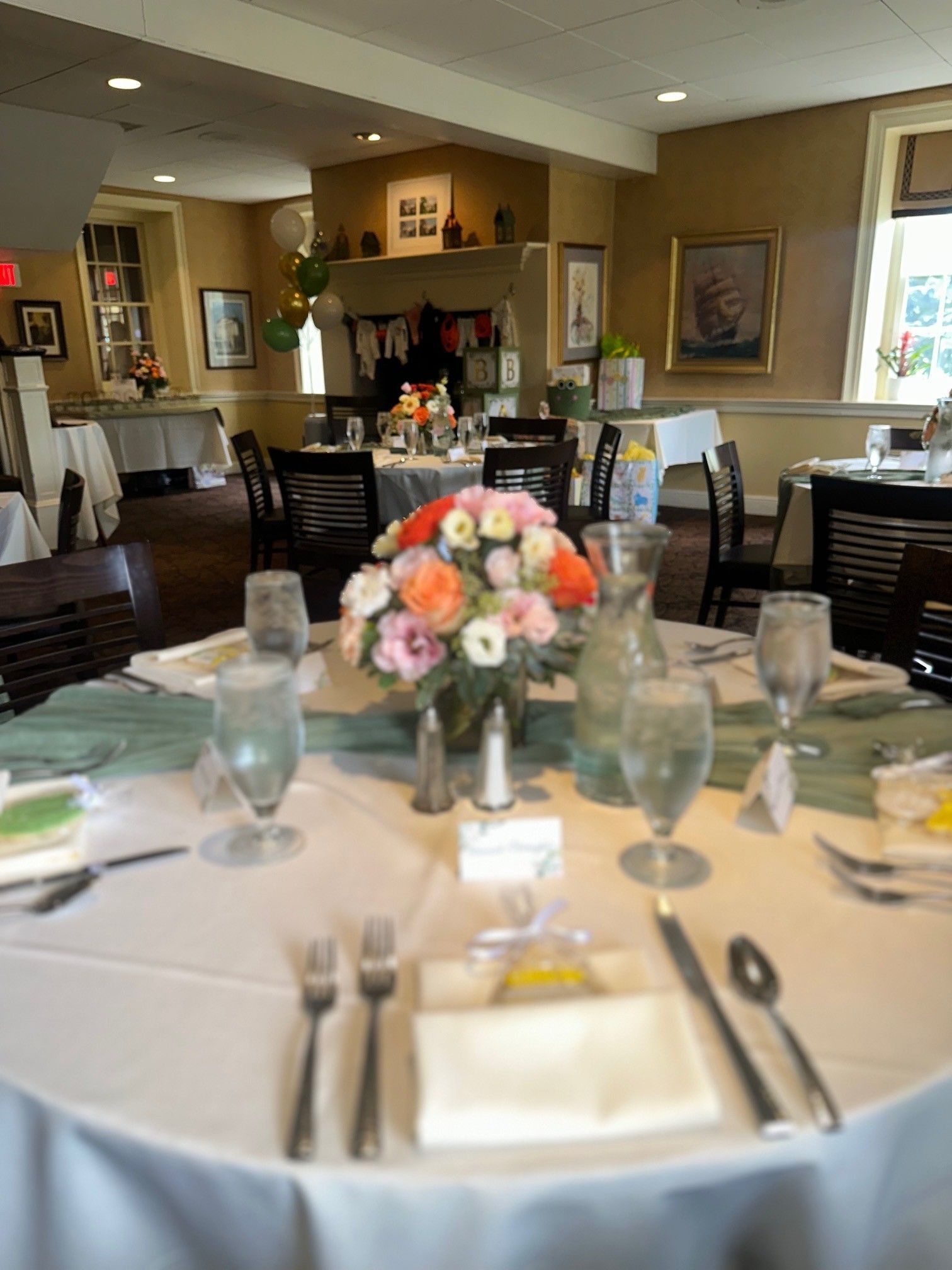 Elegantly set dining table with white linens, floral centerpiece, and warm restaurant interior in the background