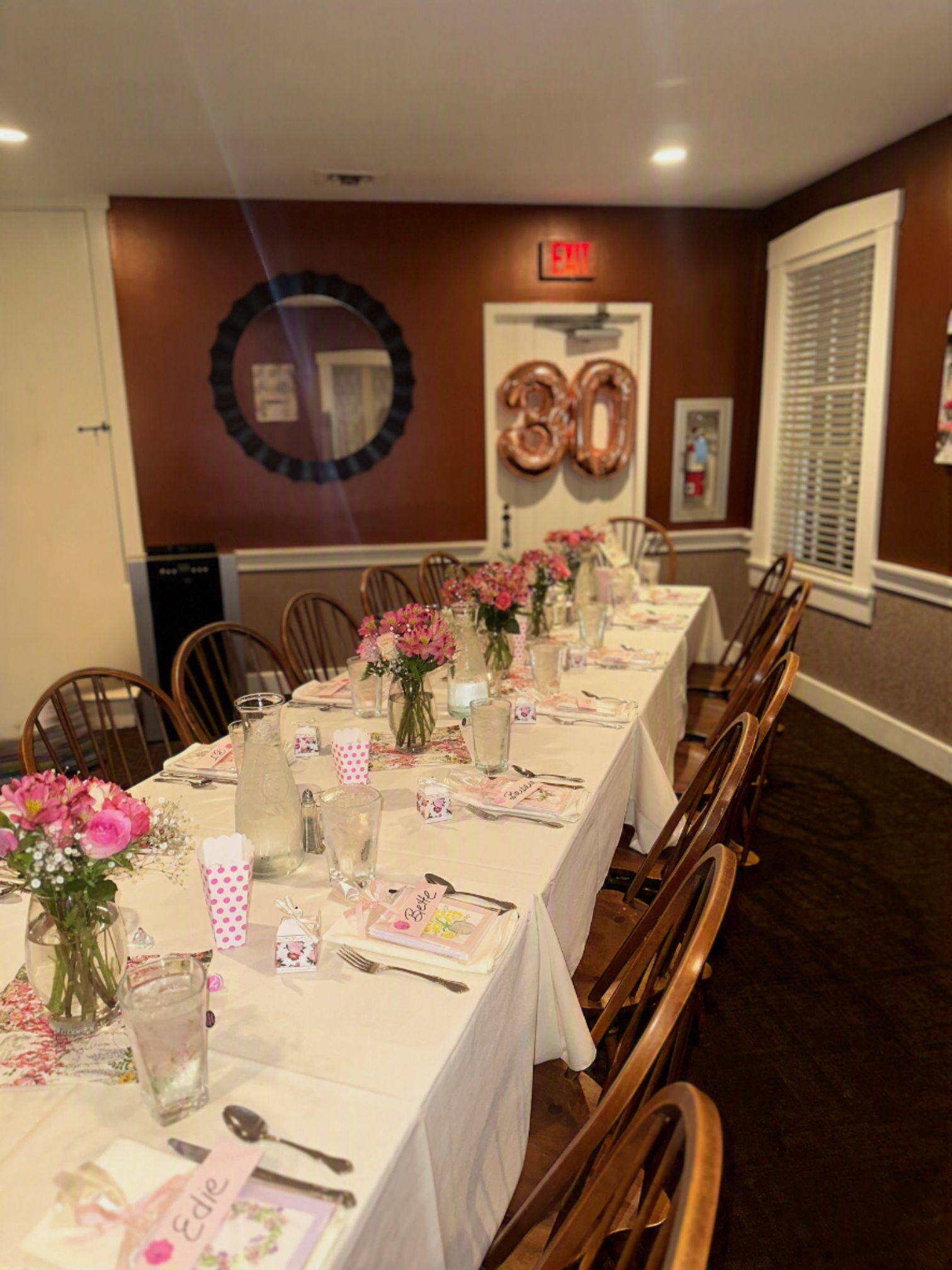 Decorated banquet table with pink floral centerpieces and gold “60” balloons in a dining room