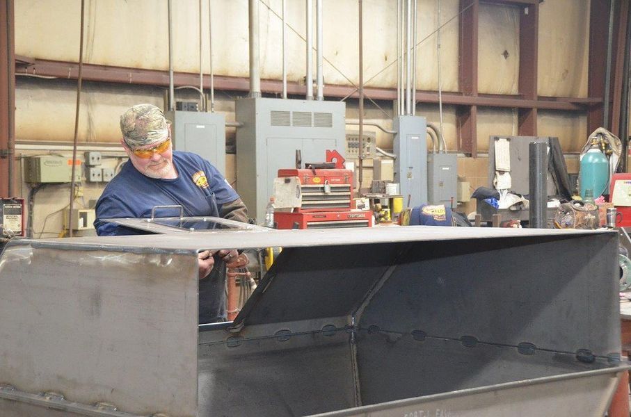 A man is working on a piece of metal in a factory.