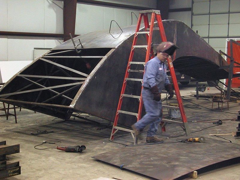 A man is welding a piece of metal in a factory