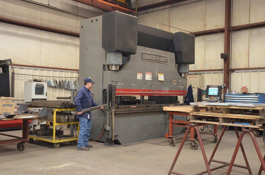 A man is standing in front of a machine in a factory.