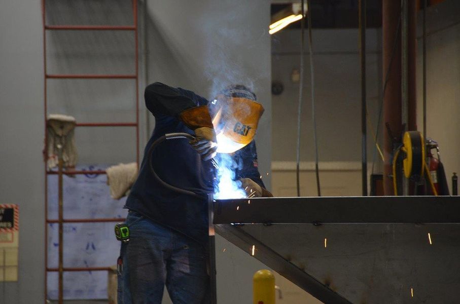 A man is welding a piece of metal in a factory.