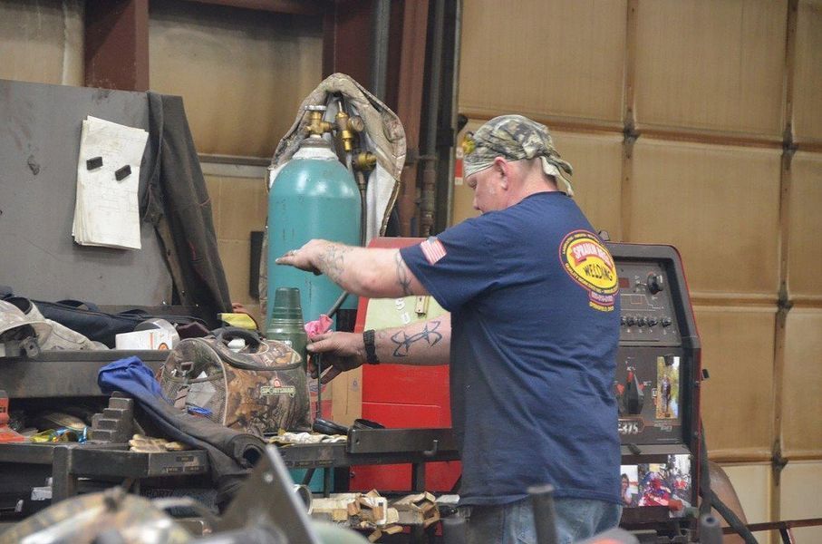 A man in a blue shirt is working on a machine in a garage.