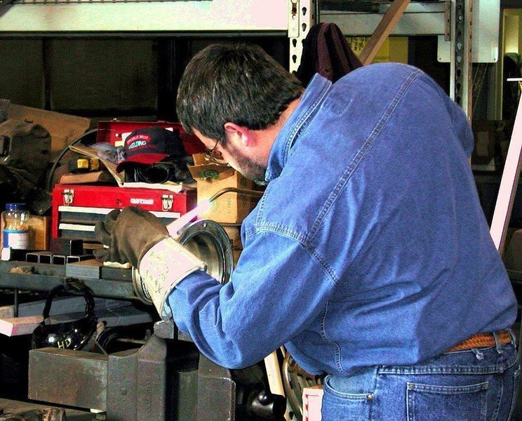 A man in a blue shirt is working on a piece of metal