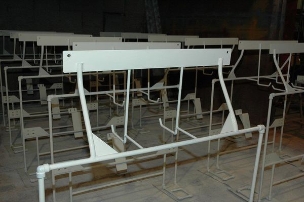 A row of white metal frames are sitting on a wooden floor.