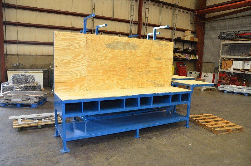 A blue workbench with a wooden top is sitting in a warehouse.