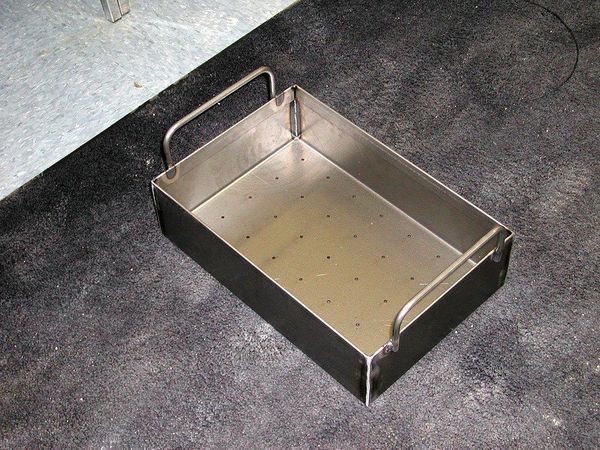A metal tray with handles is sitting on the ground