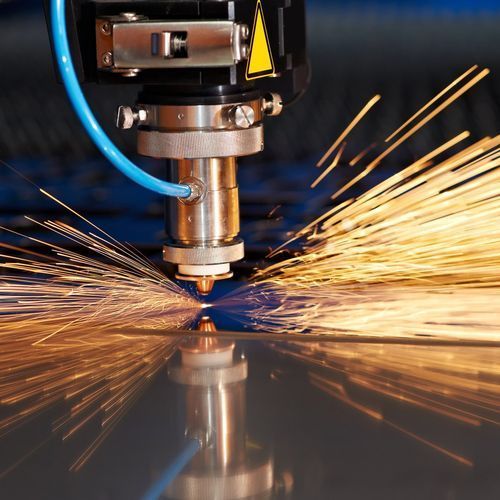 A machine is cutting a piece of metal with sparks coming out of it