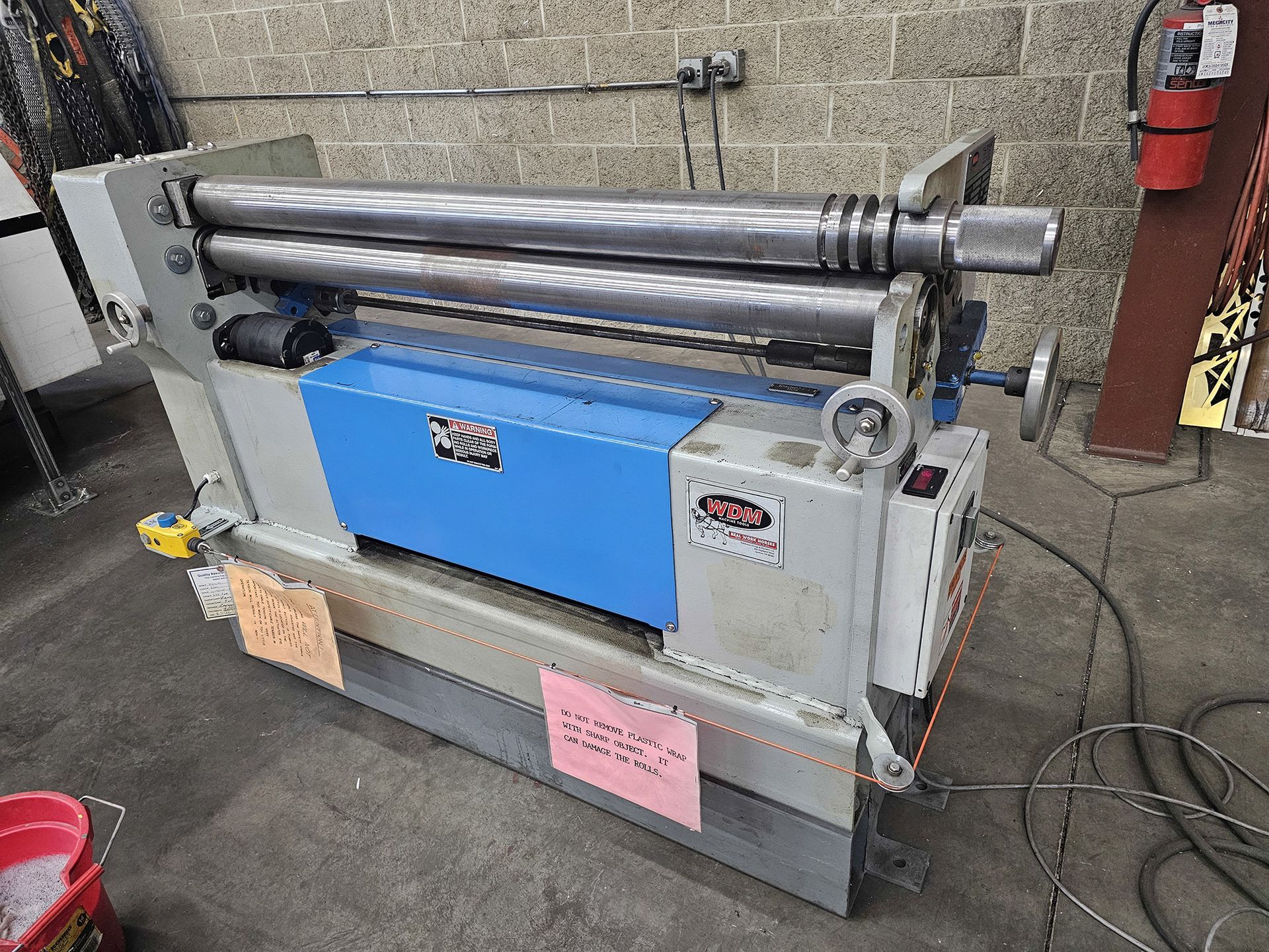 A machine is sitting in a garage next to a fire extinguisher.