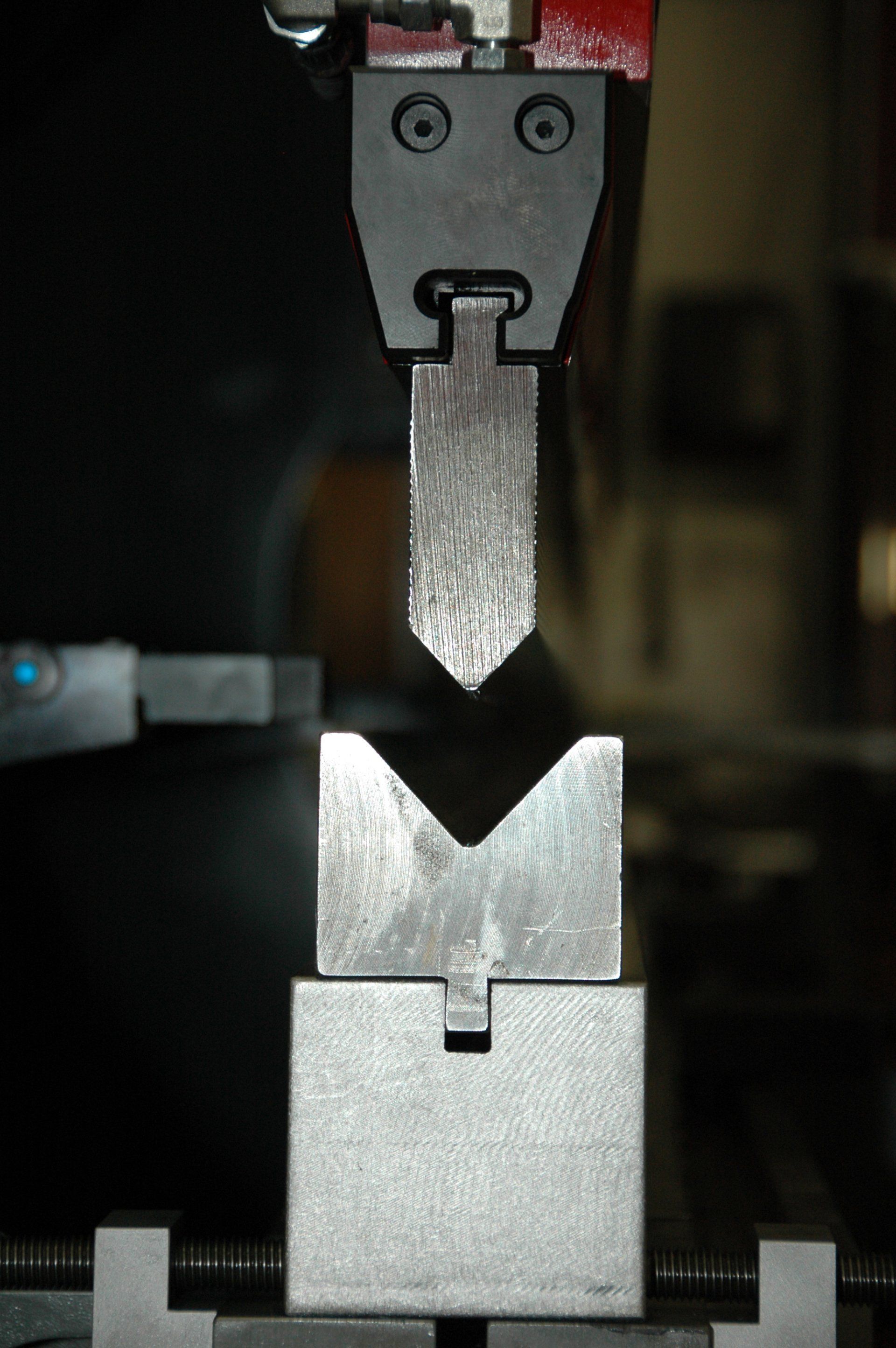 A machine is cutting a piece of metal with a face on it.