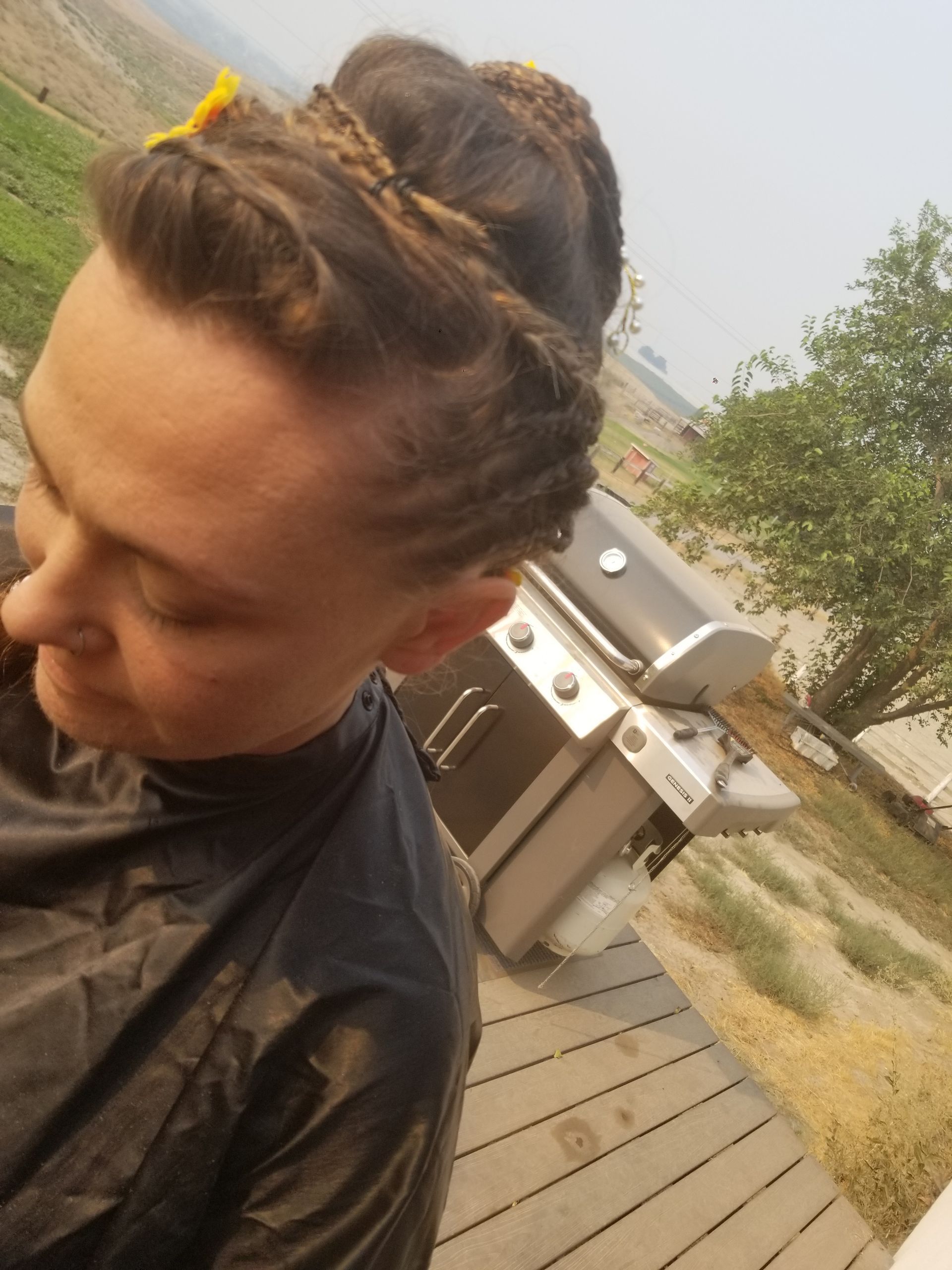 A man with braids in his hair is standing in front of a grill