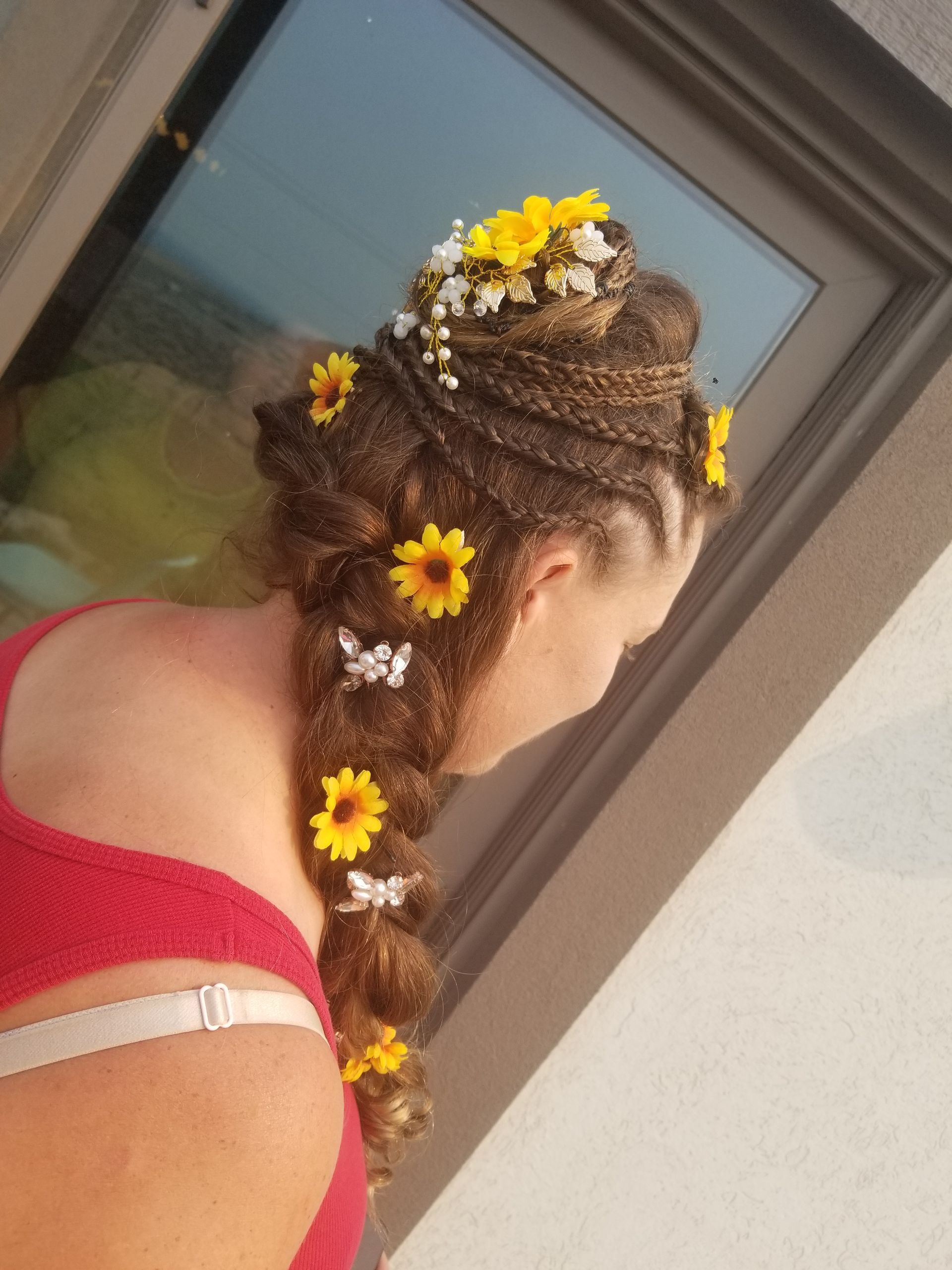 A woman wearing a braid with yellow flowers and butterflies in her hair