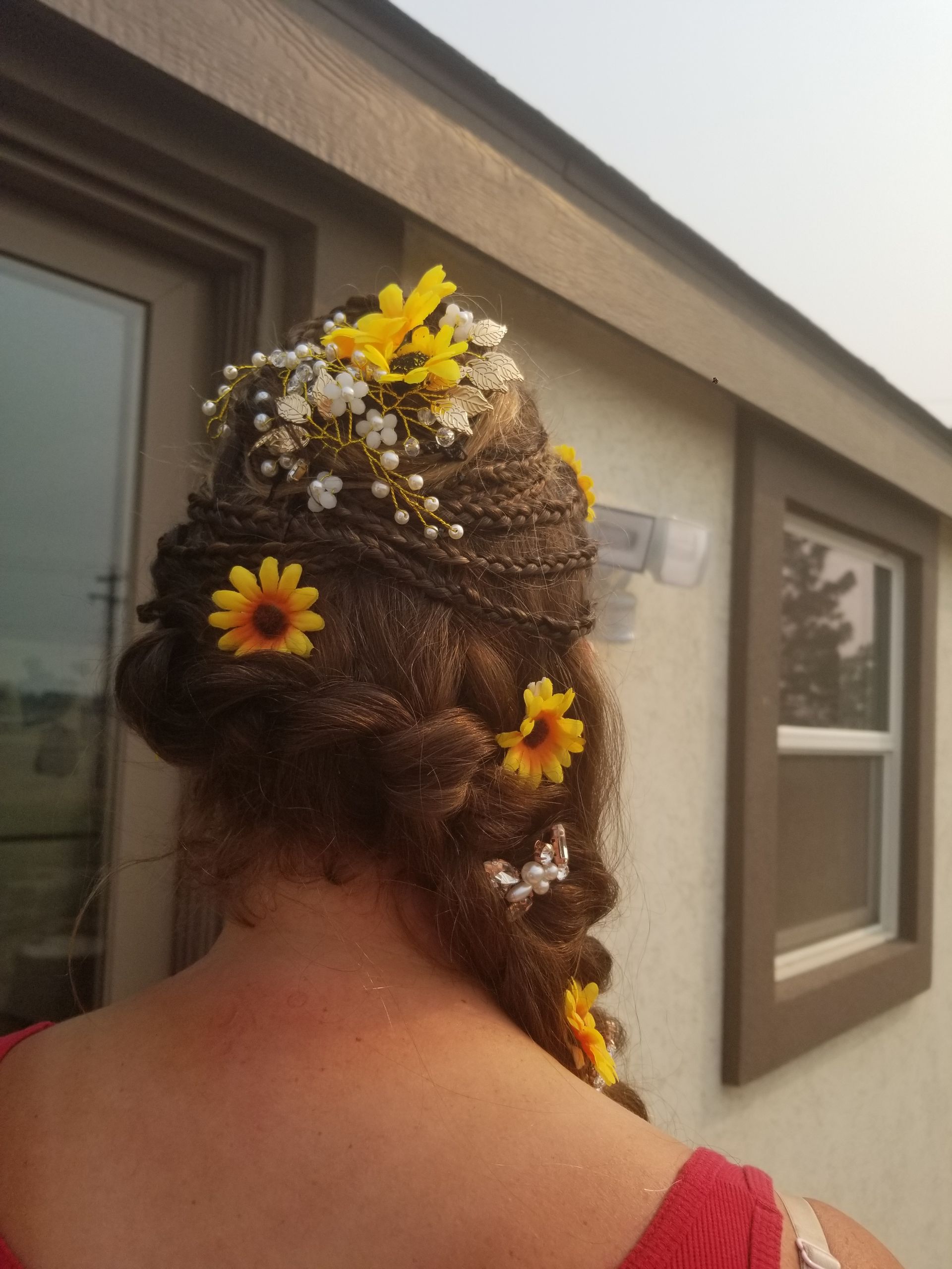 A woman with flowers in her hair is standing in front of a building.