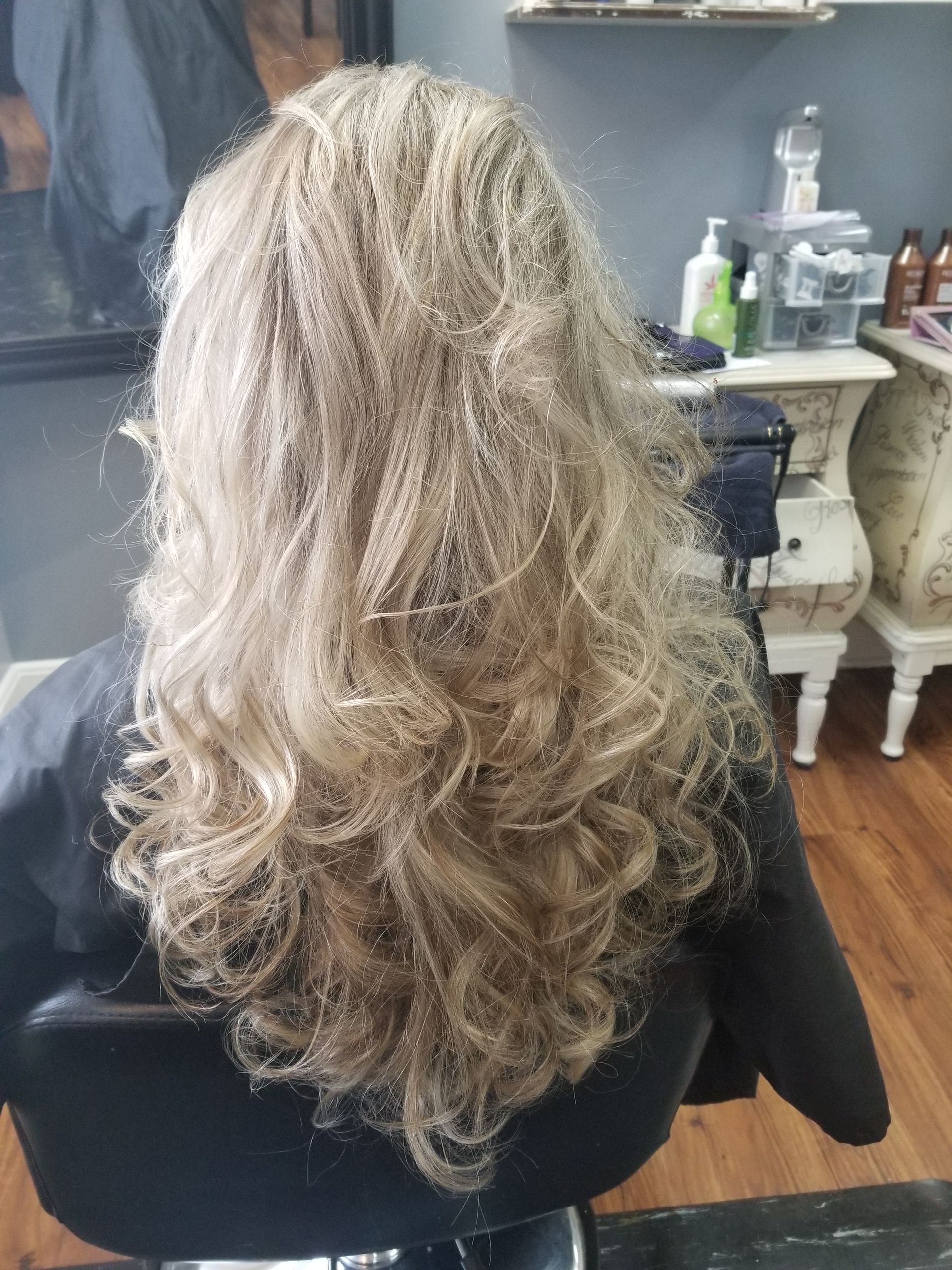 A woman is sitting in a chair with her hair in a salon.