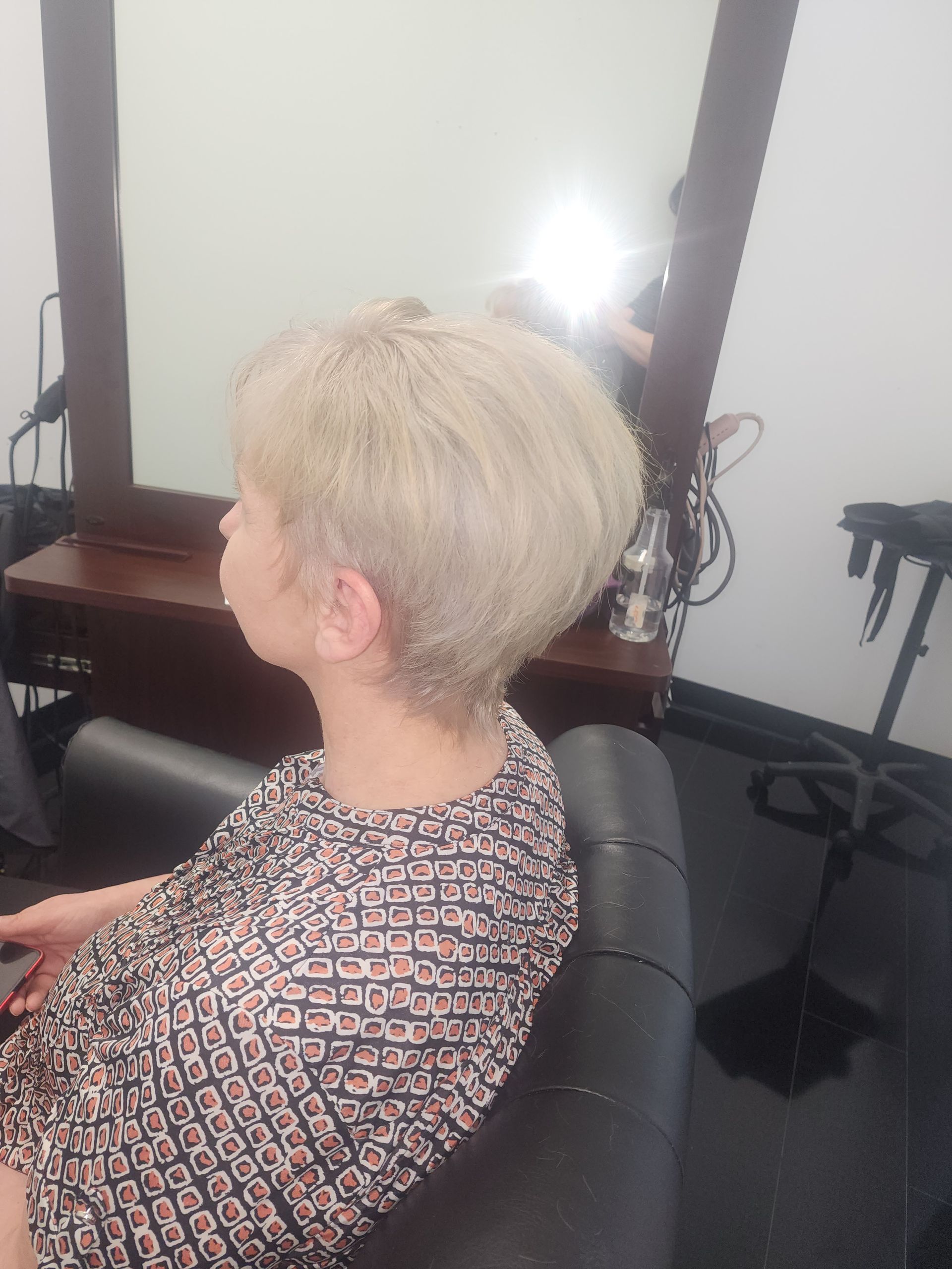 A woman is sitting in a chair in front of a mirror.