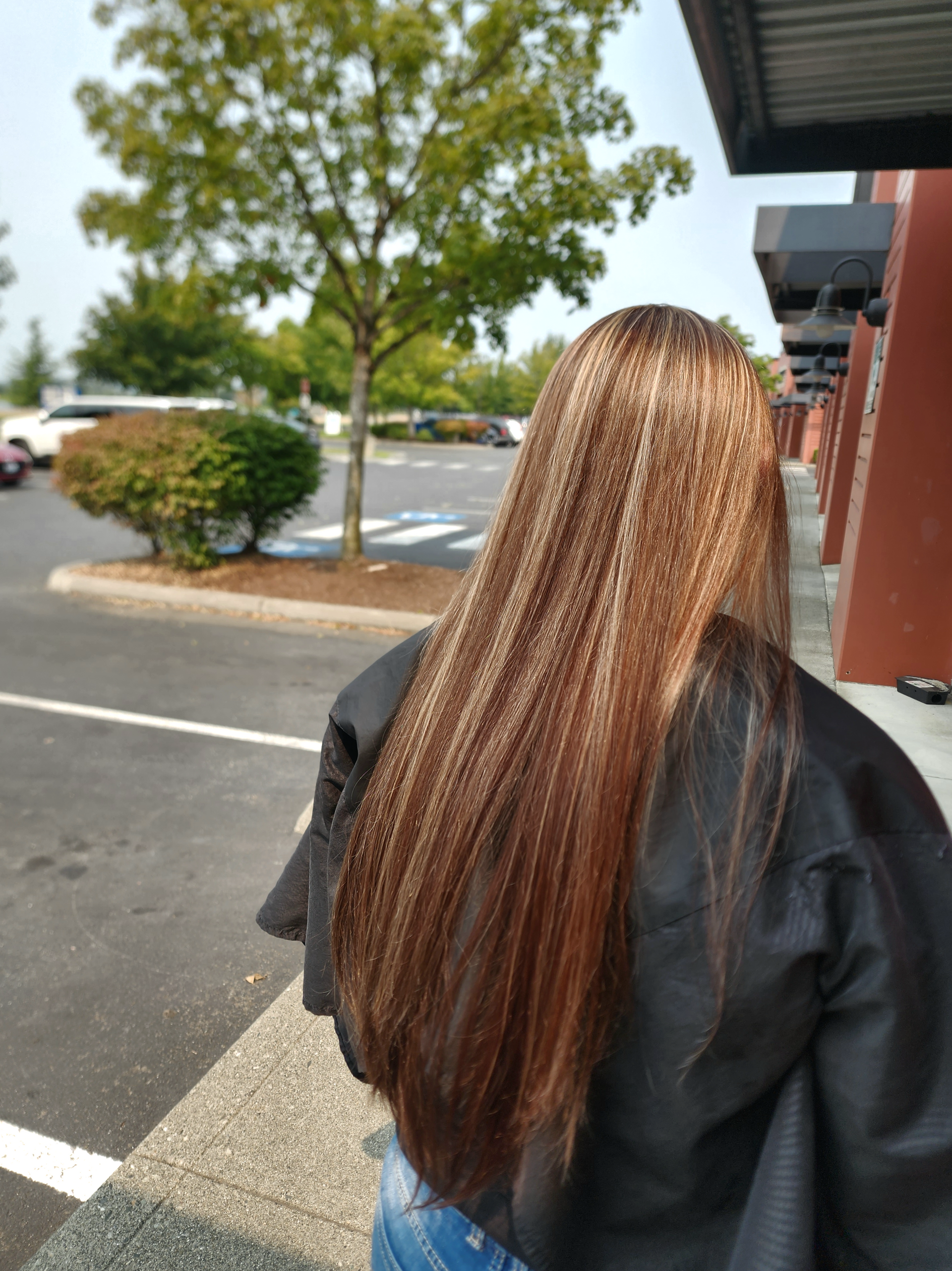 A woman with long brown hair is standing in a parking lot.