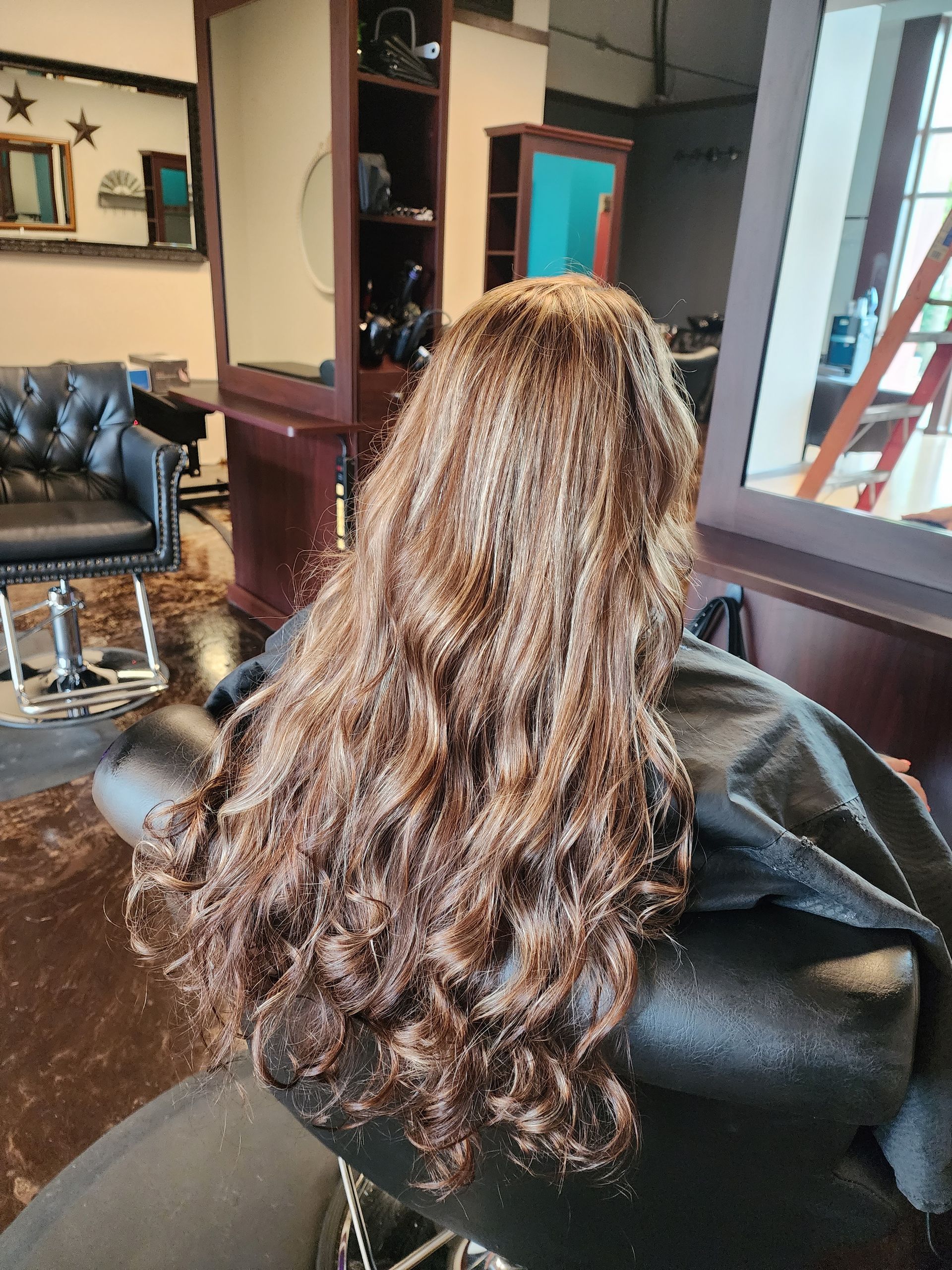 A woman with long hair is sitting in a chair in a salon.