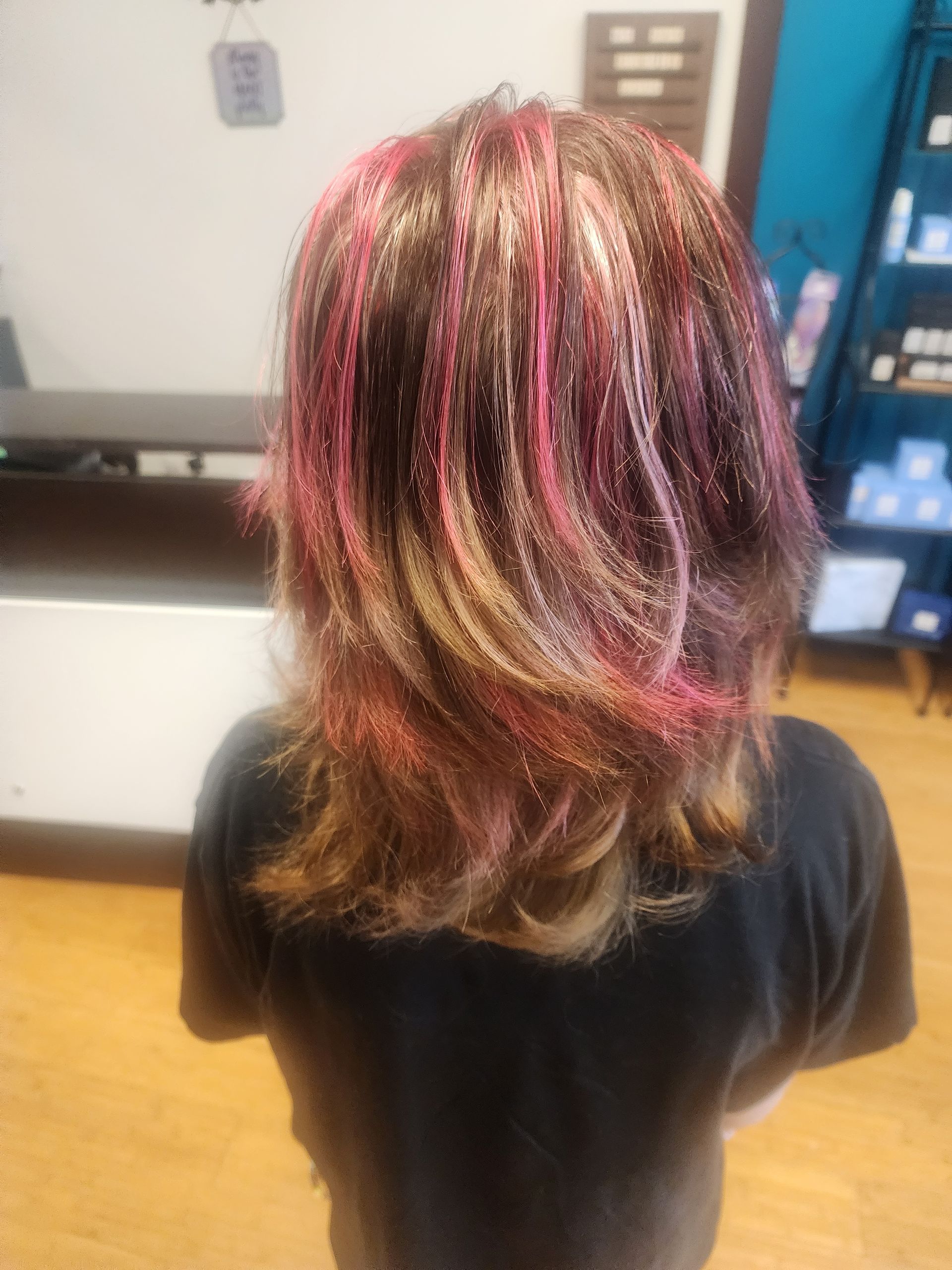 A woman with pink and gold hair is standing in a room.