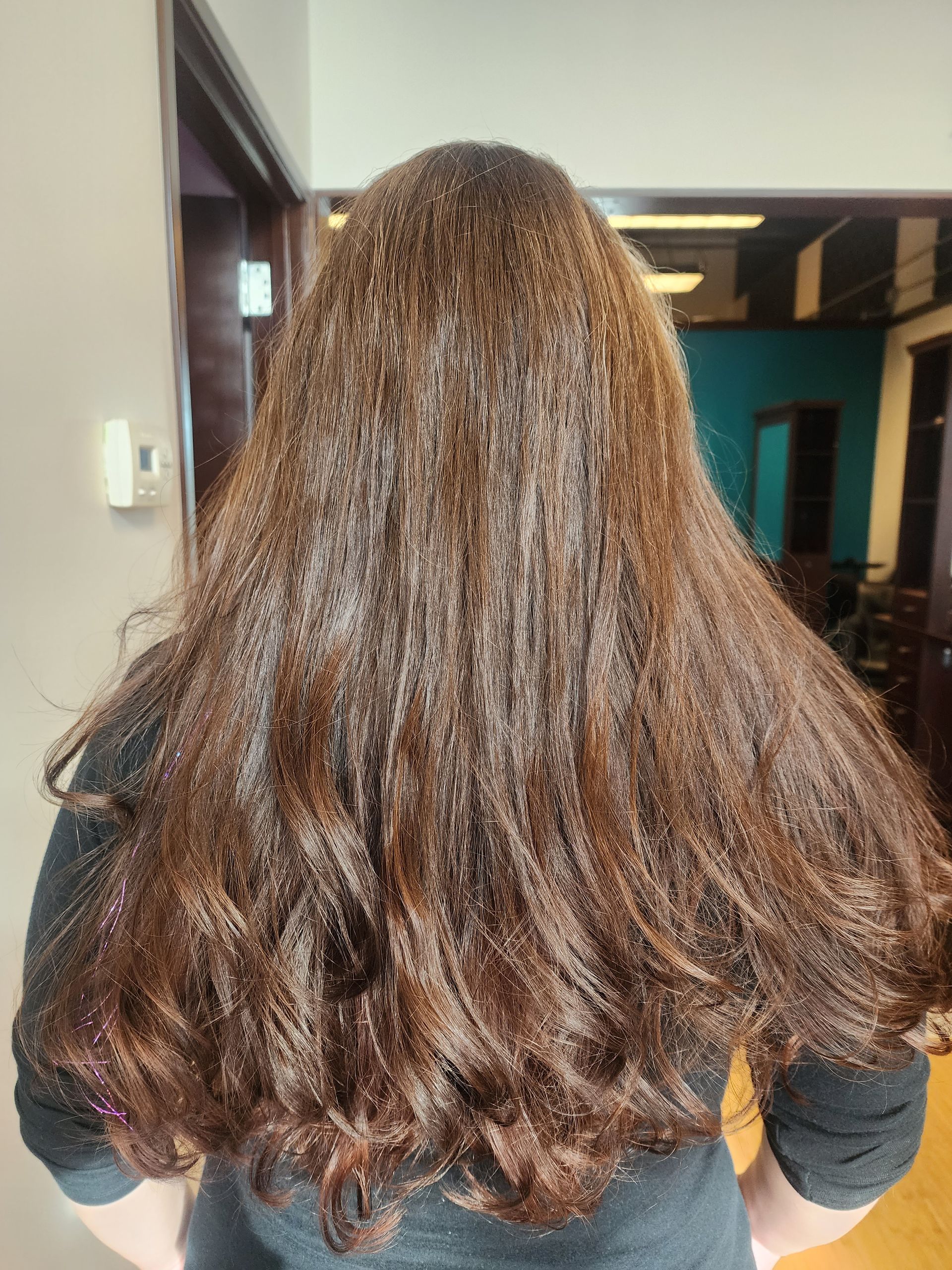 A woman with long brown hair is standing in a room.