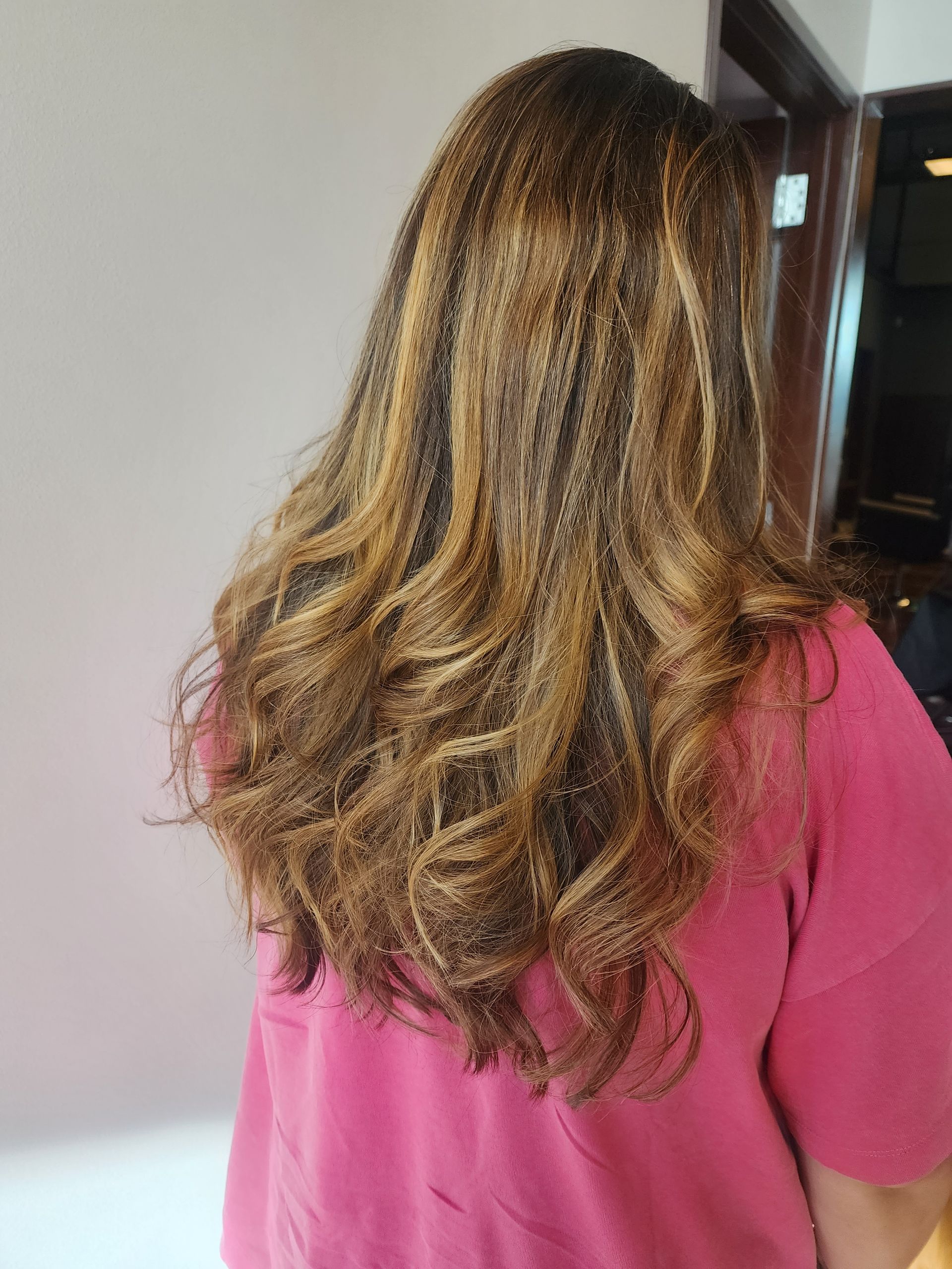 A woman with long brown hair is wearing a pink shirt.