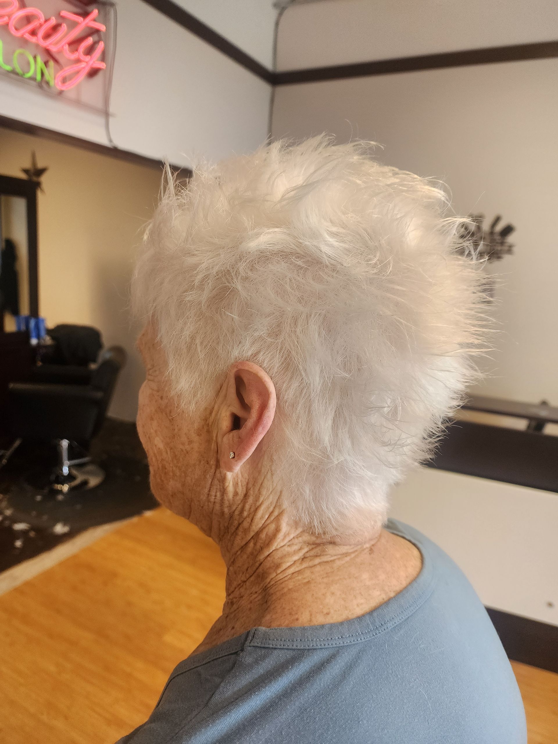 A woman with gray hair is sitting at a table in a salon.