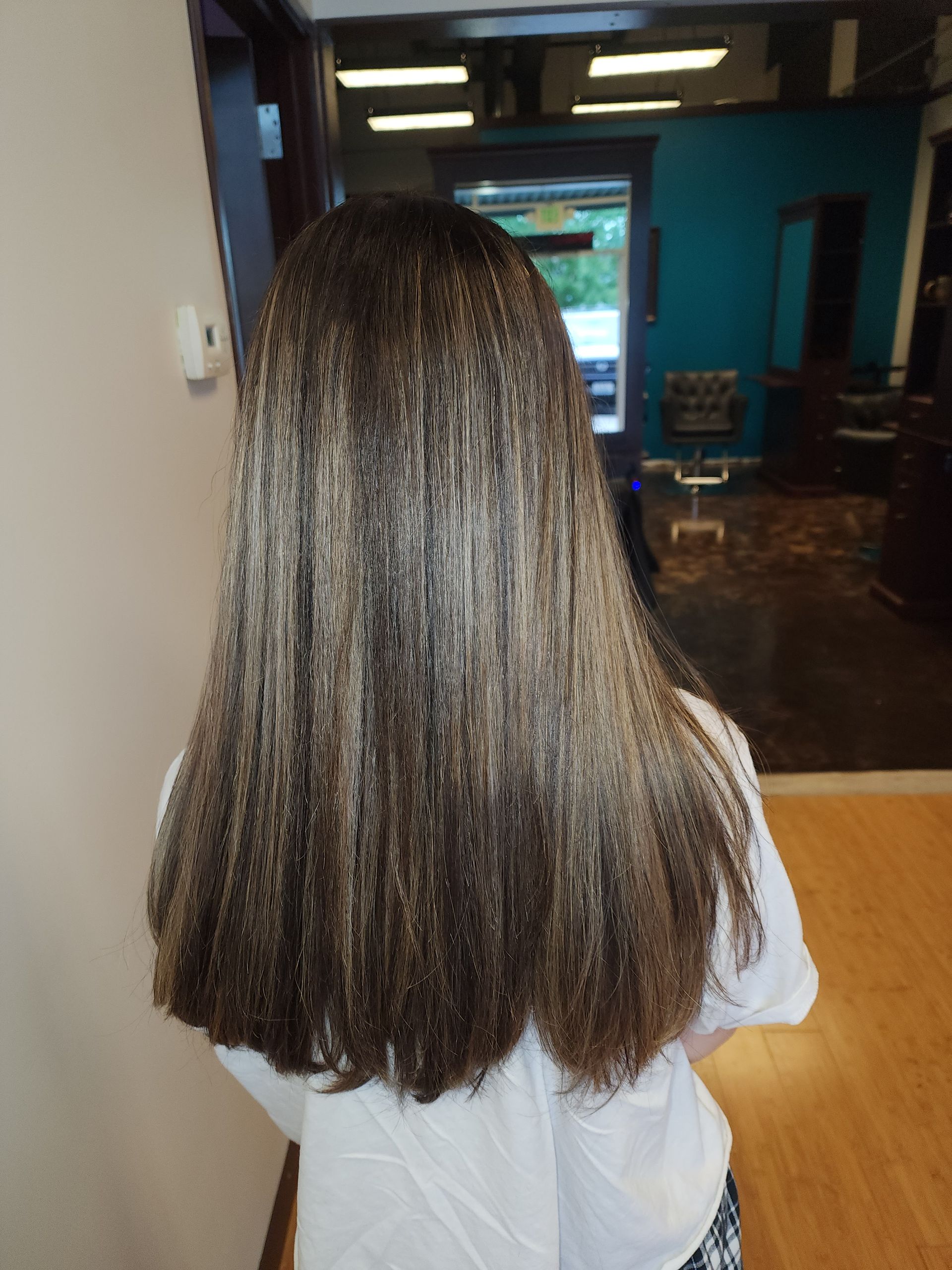 A girl with long brown hair is standing in a room