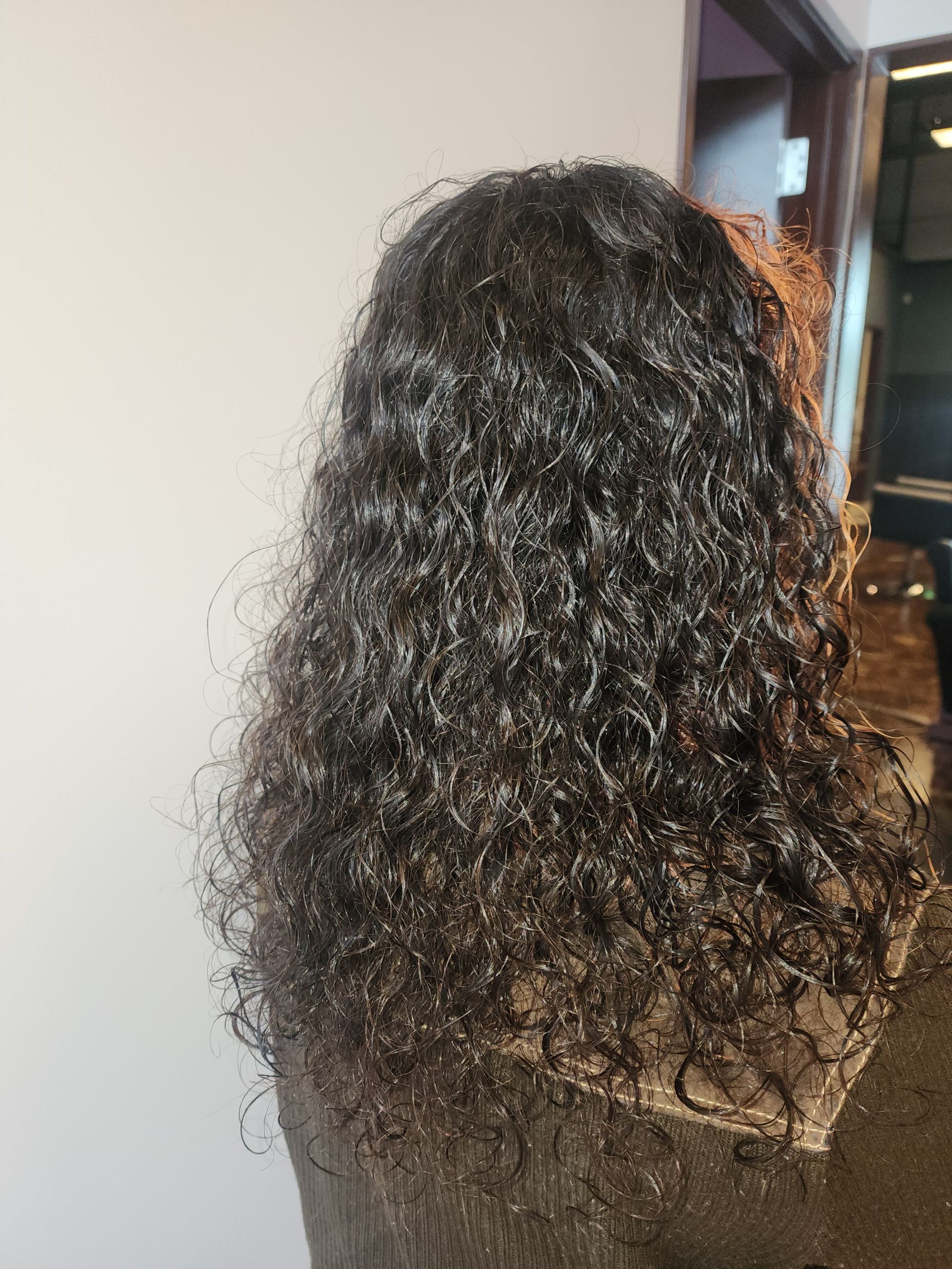 A woman with curly hair is wearing a wig.