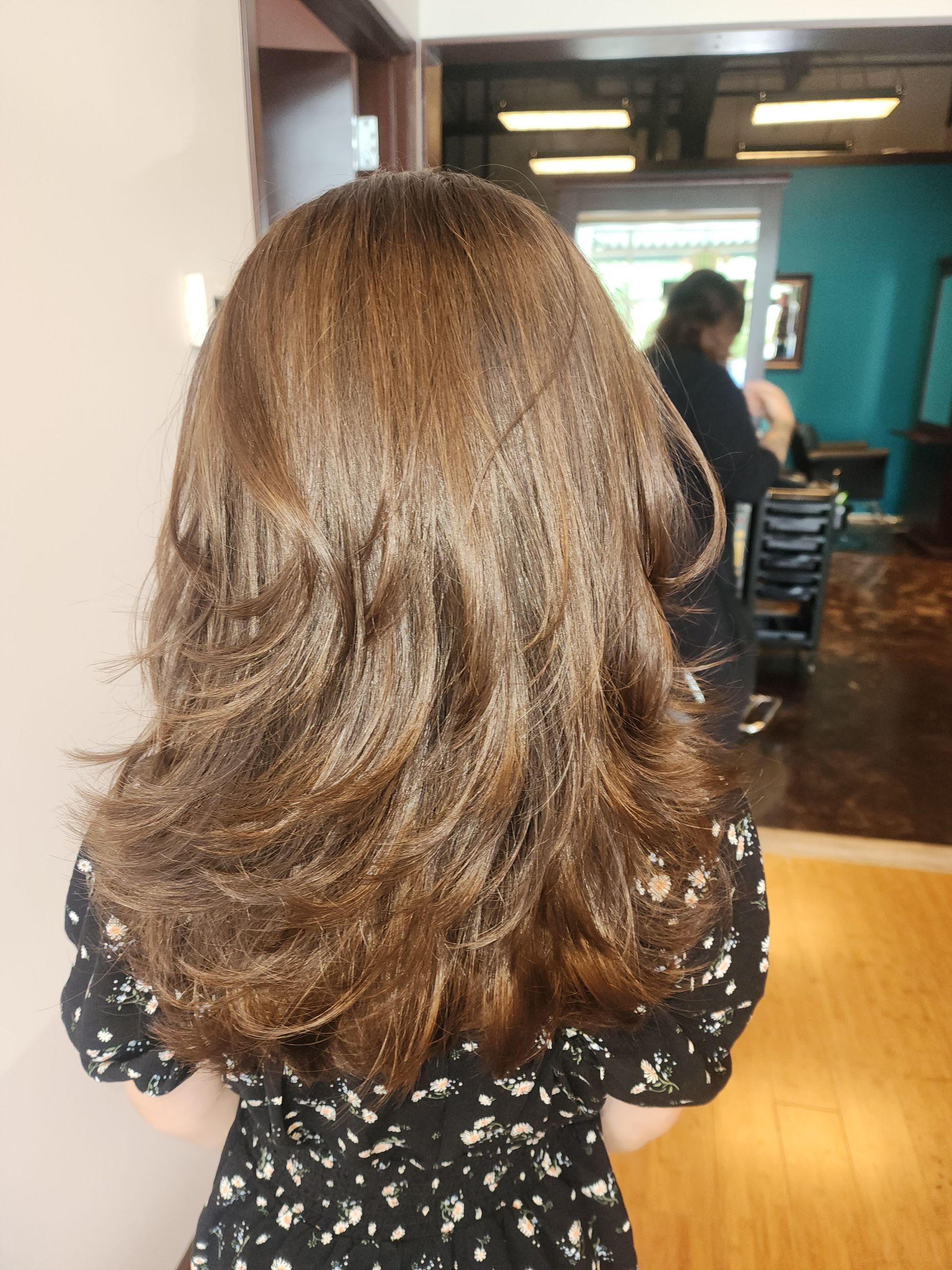 A woman with long brown hair is standing in front of a mirror.