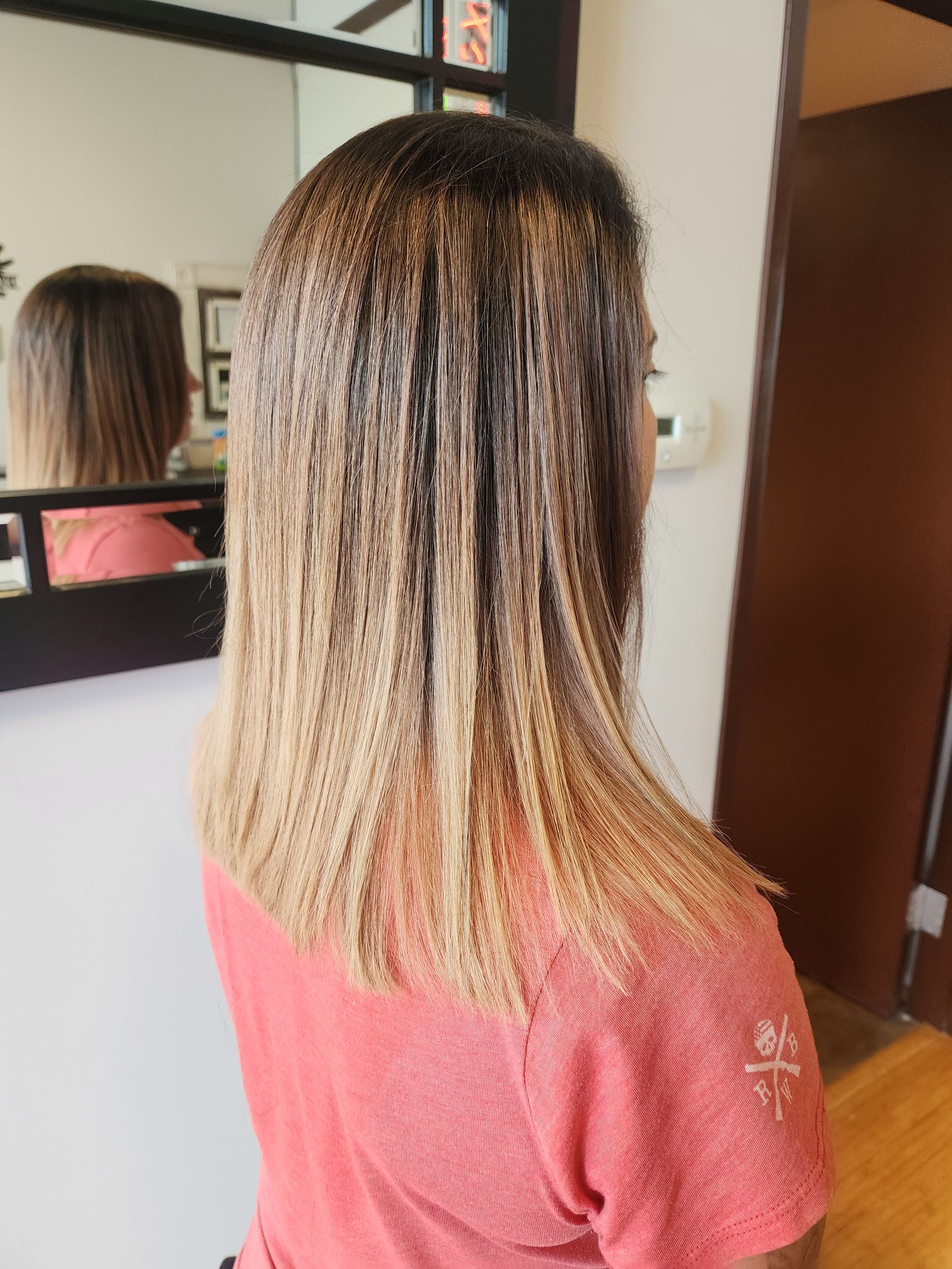 A woman with long hair is standing in front of a mirror.