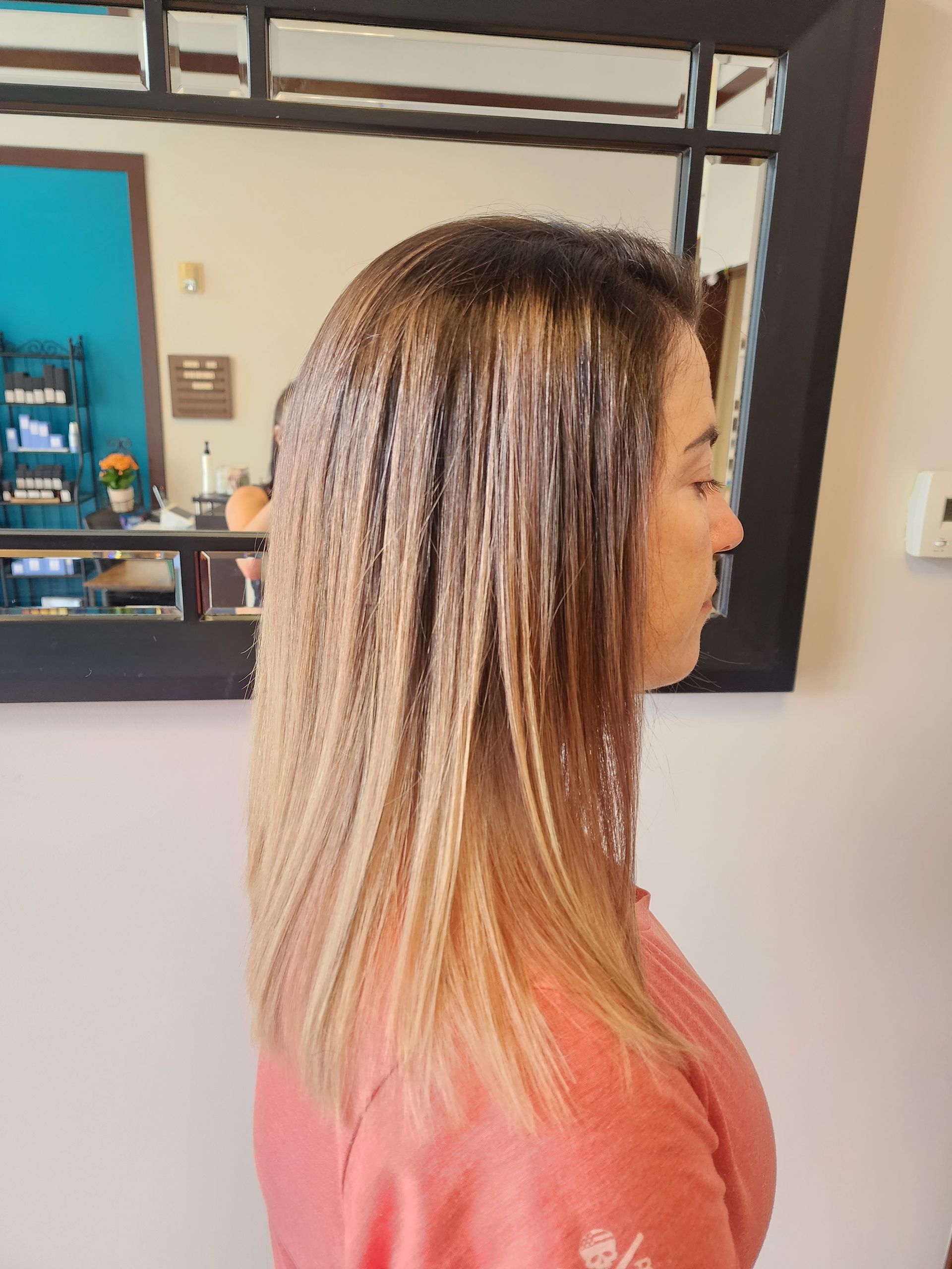 A woman with long hair is standing in front of a mirror.