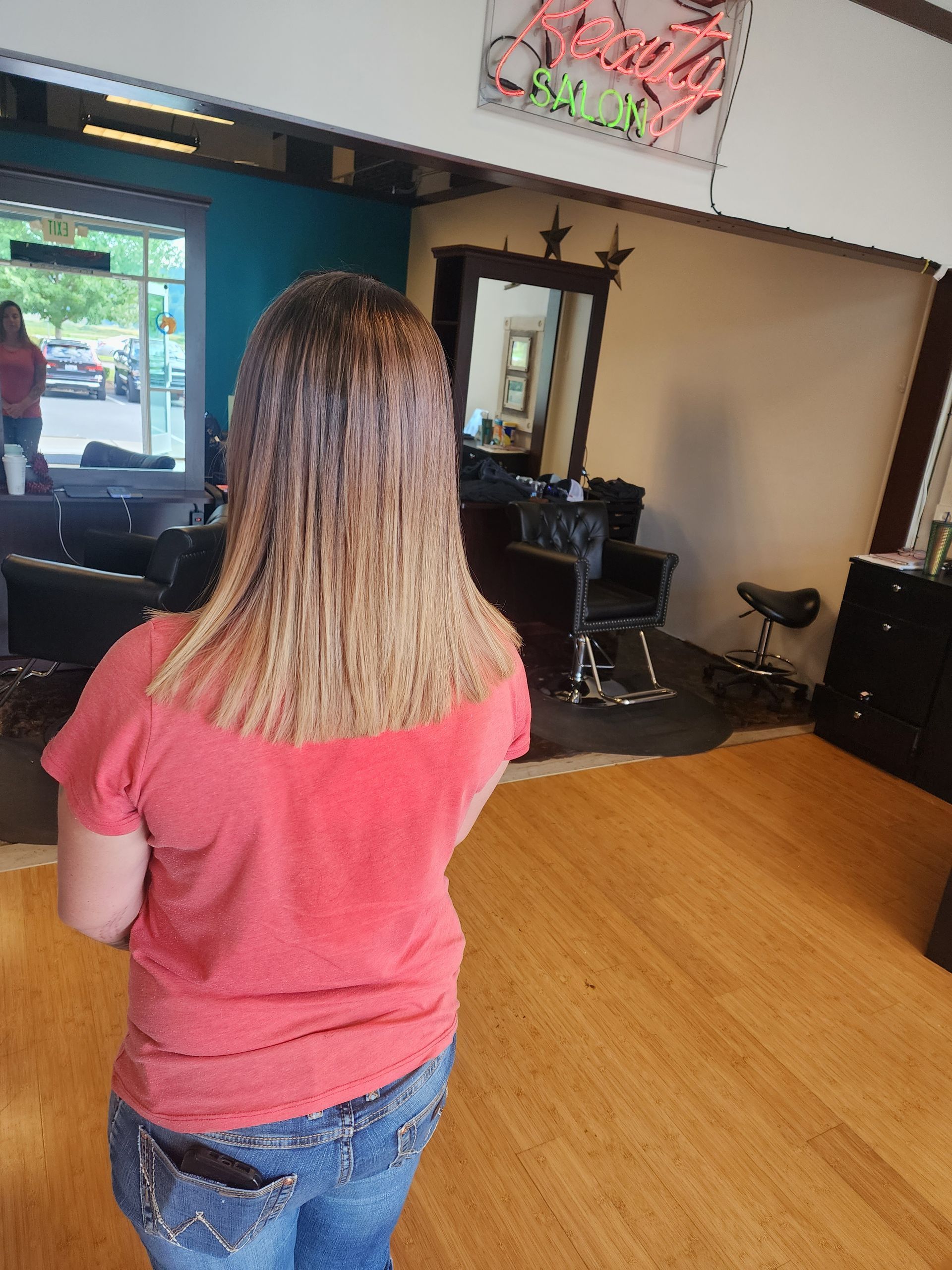 A woman is standing in a salon with her back to the camera.