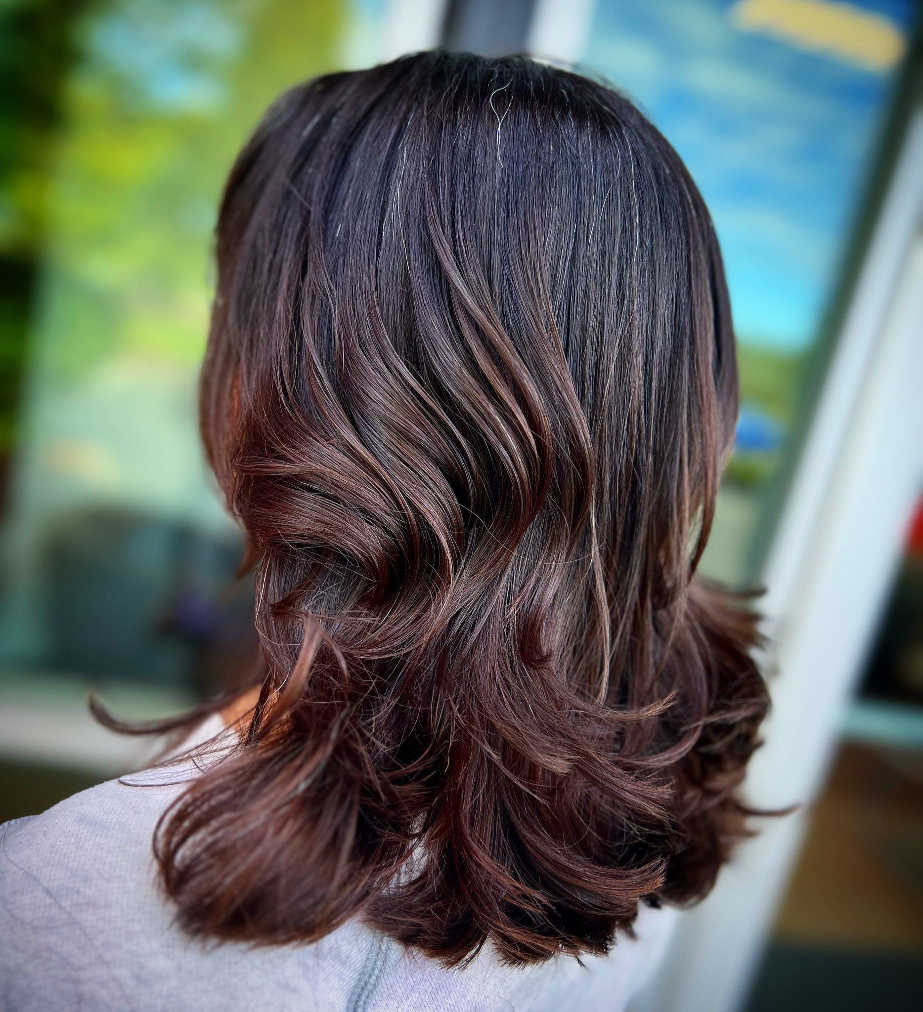 A woman with long brown hair is wearing a grey sweater