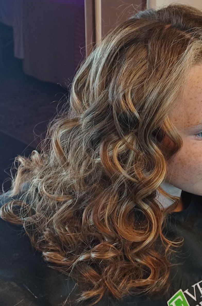 A woman with long curly hair is wearing a black cape.