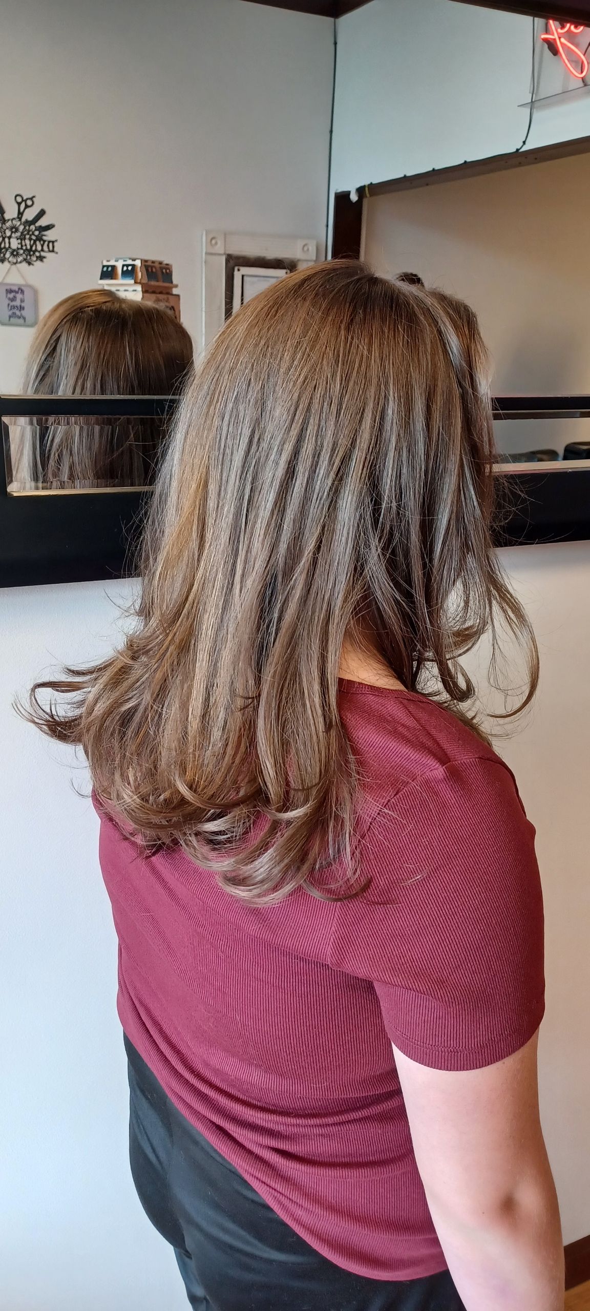 A woman with long brown hair is standing in front of a mirror.
