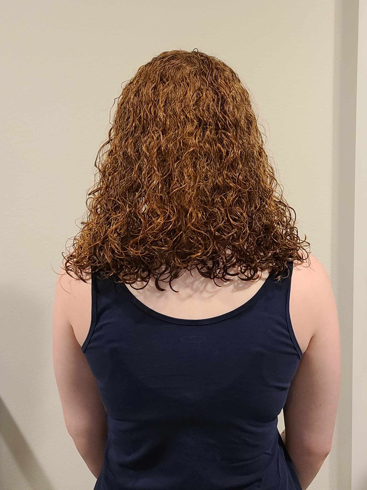 A woman with curly hair is wearing a black tank top.